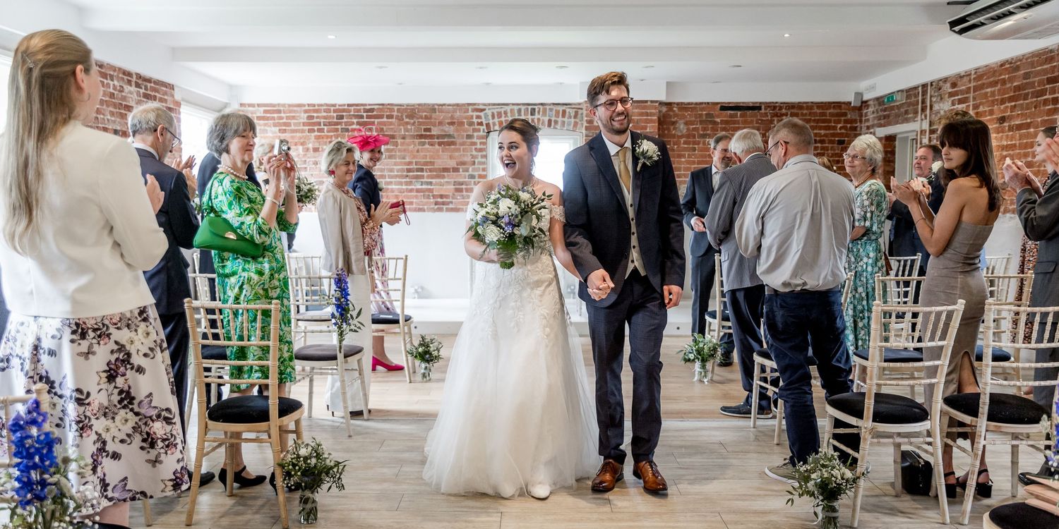 Panoramic view of wedding ceremony in converted industrial space with brick walls.