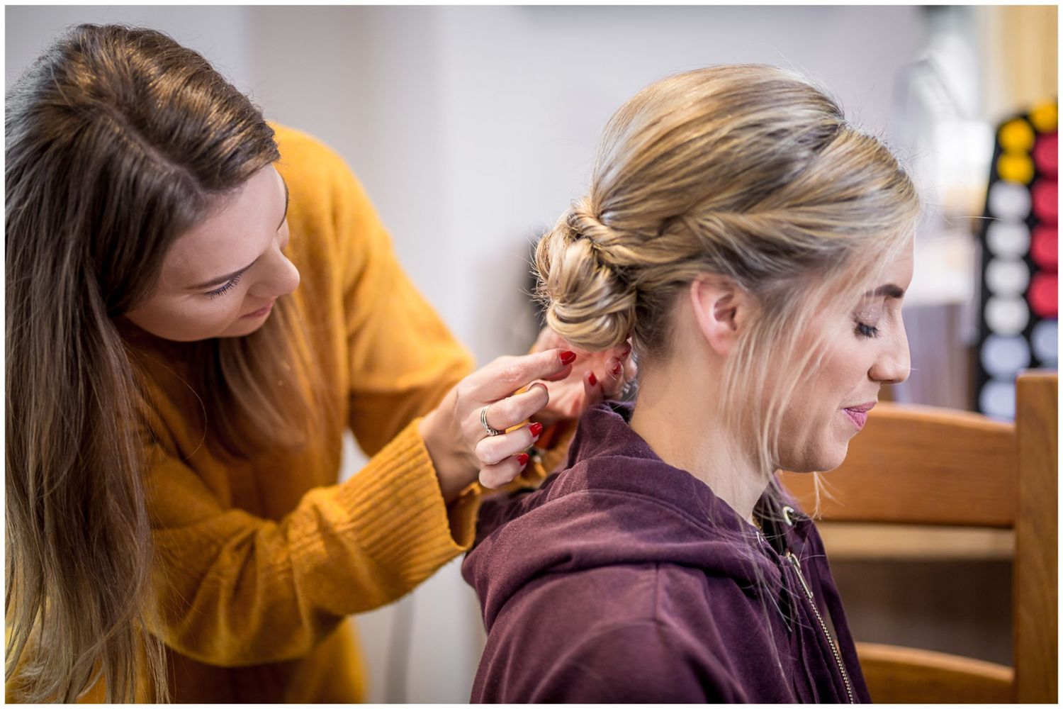 Hair stylist in yellow sweater creating elegant bridal updo.