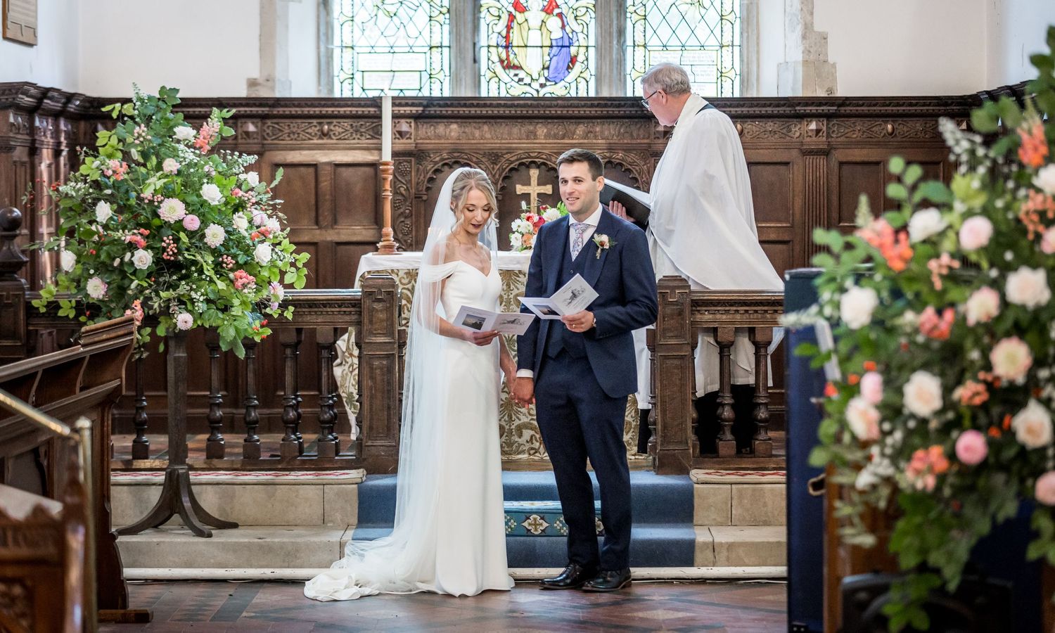Traditional church wedding ceremony with floral arrangements and wooden interior details.