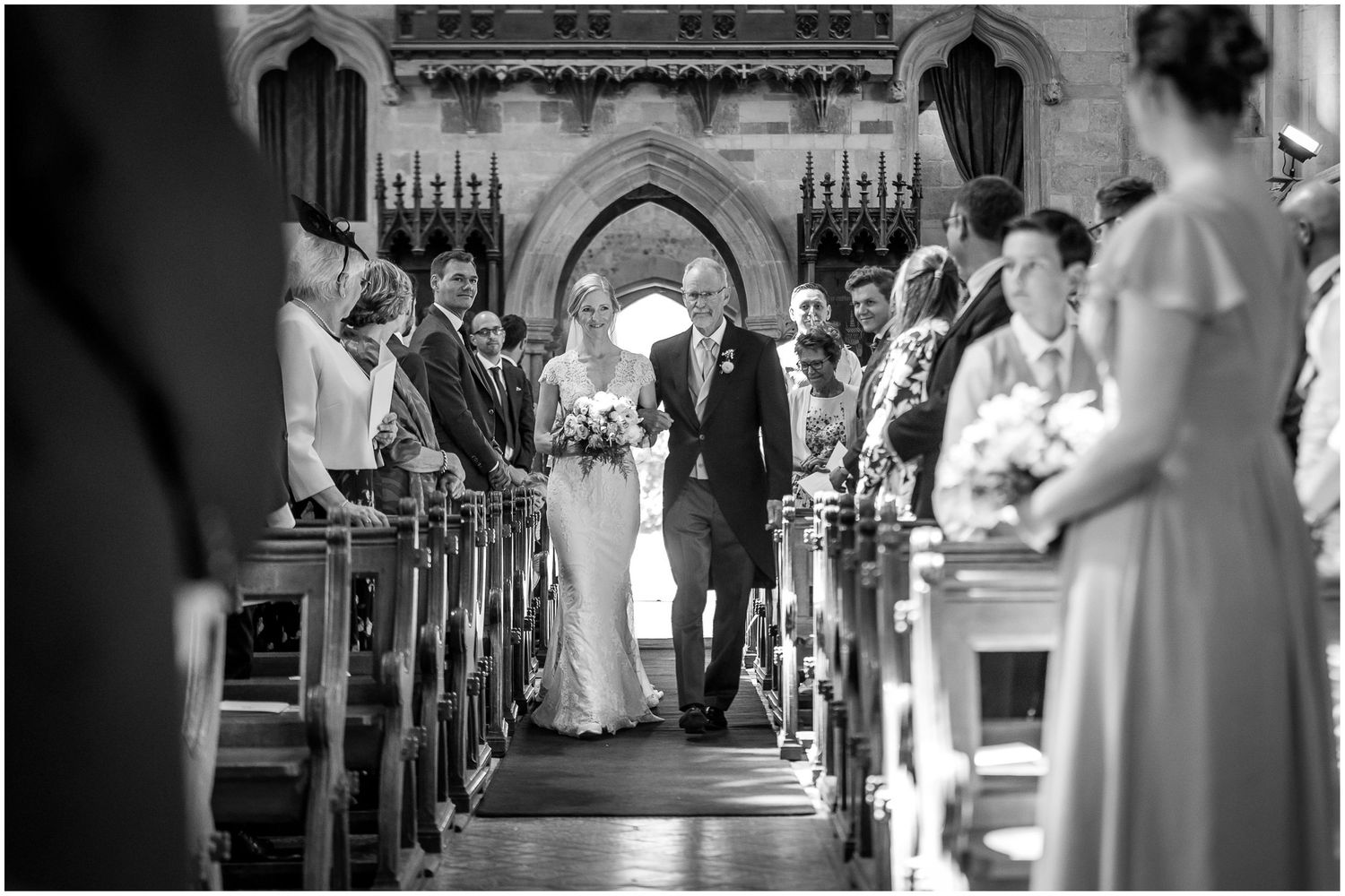 Wedding ceremony procession in a grand church with stone architecture.