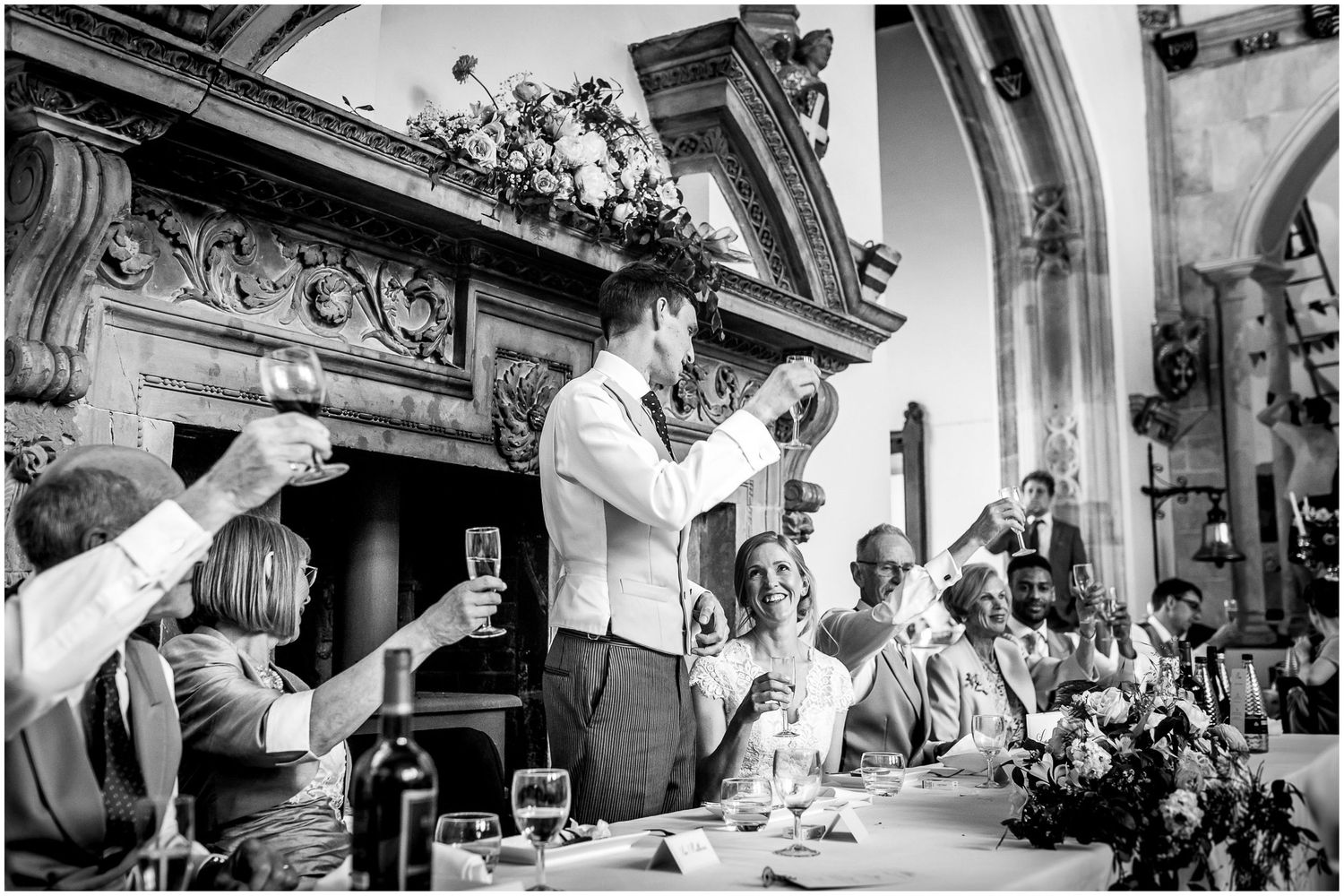 A celebratory toast moment during a wedding reception in a historic venue with ornate details.