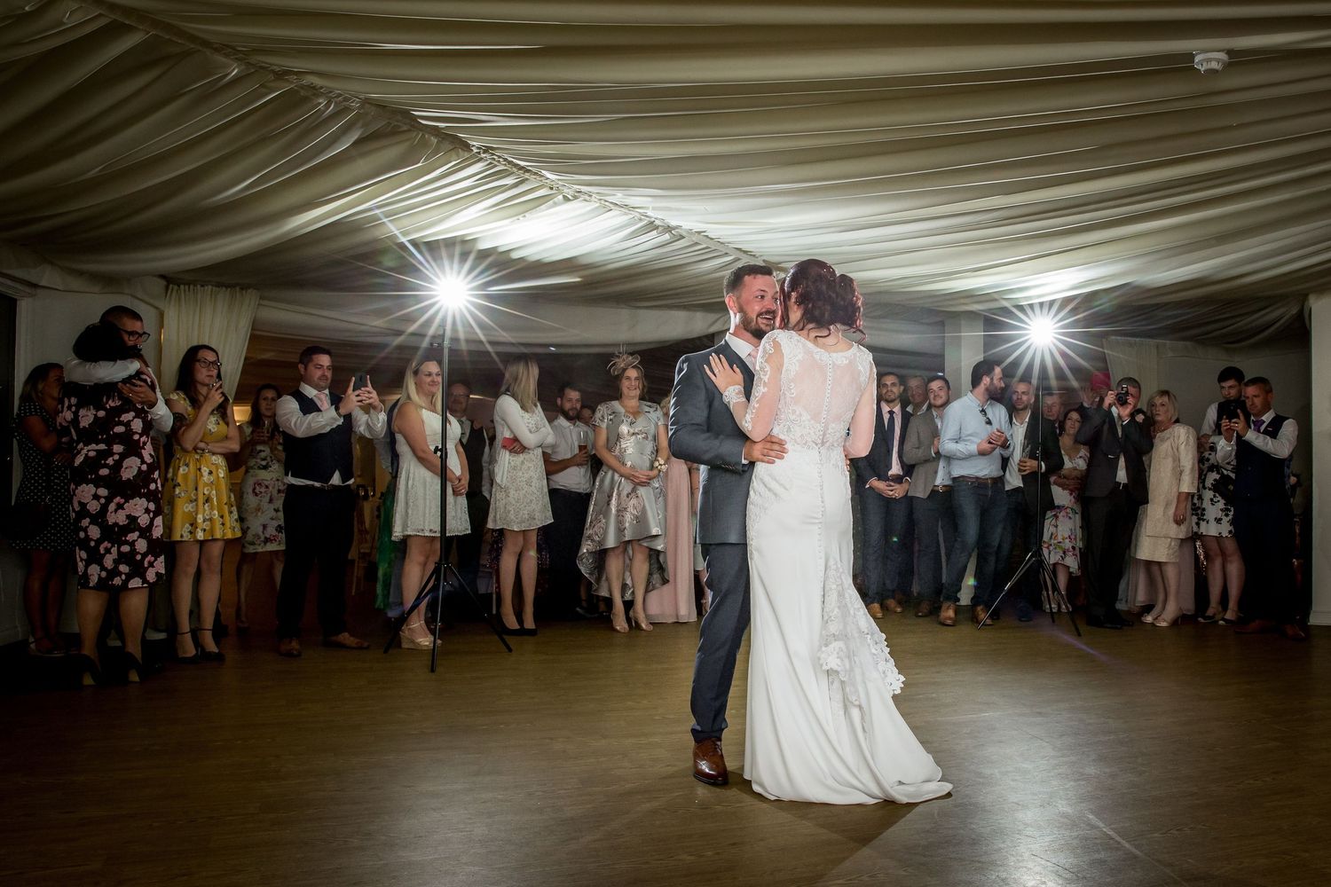Wedding reception first dance under draped fabric ceiling with guests watching.