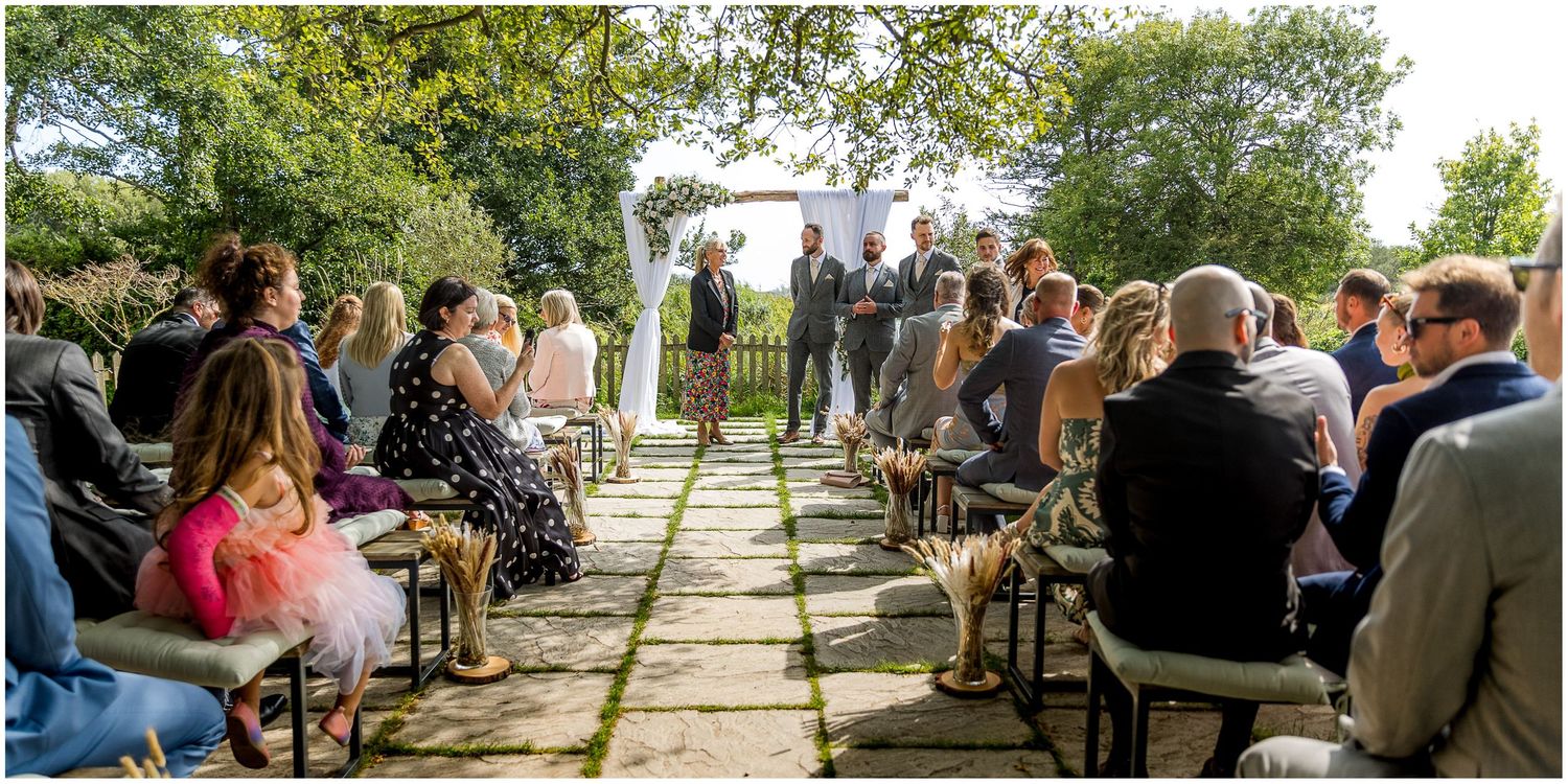 Outdoor wedding ceremony setup with stone pathway and white chairs for guests.