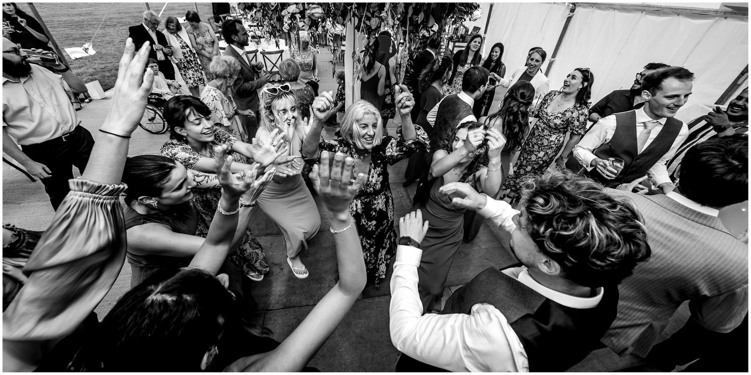 Wedding guests dance and celebrate together on a lively dance floor during the reception.