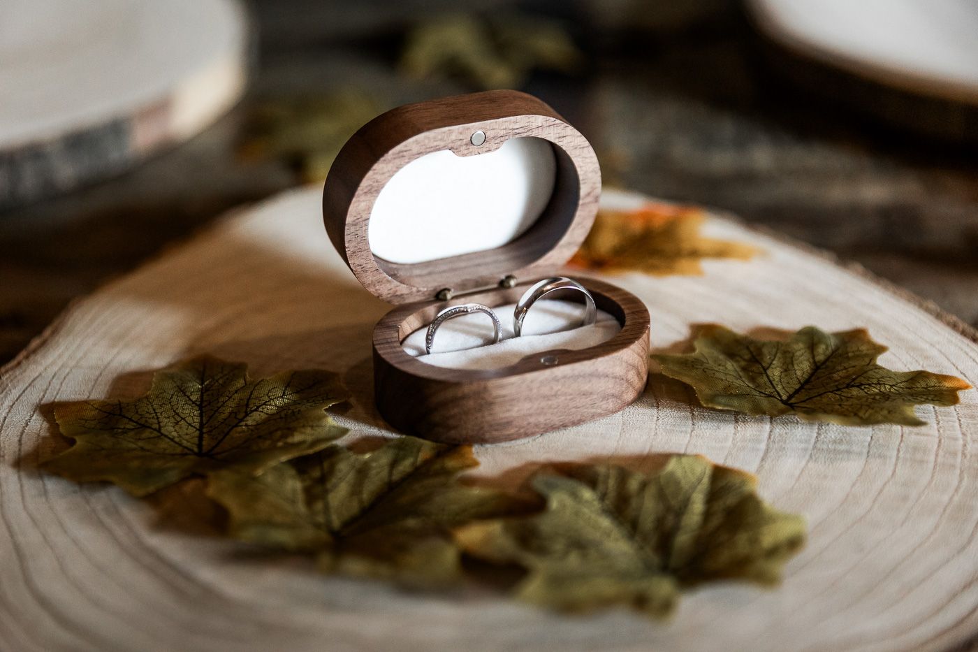 Wedding rings and accessories artistically arranged on wooden surface with natural elements.