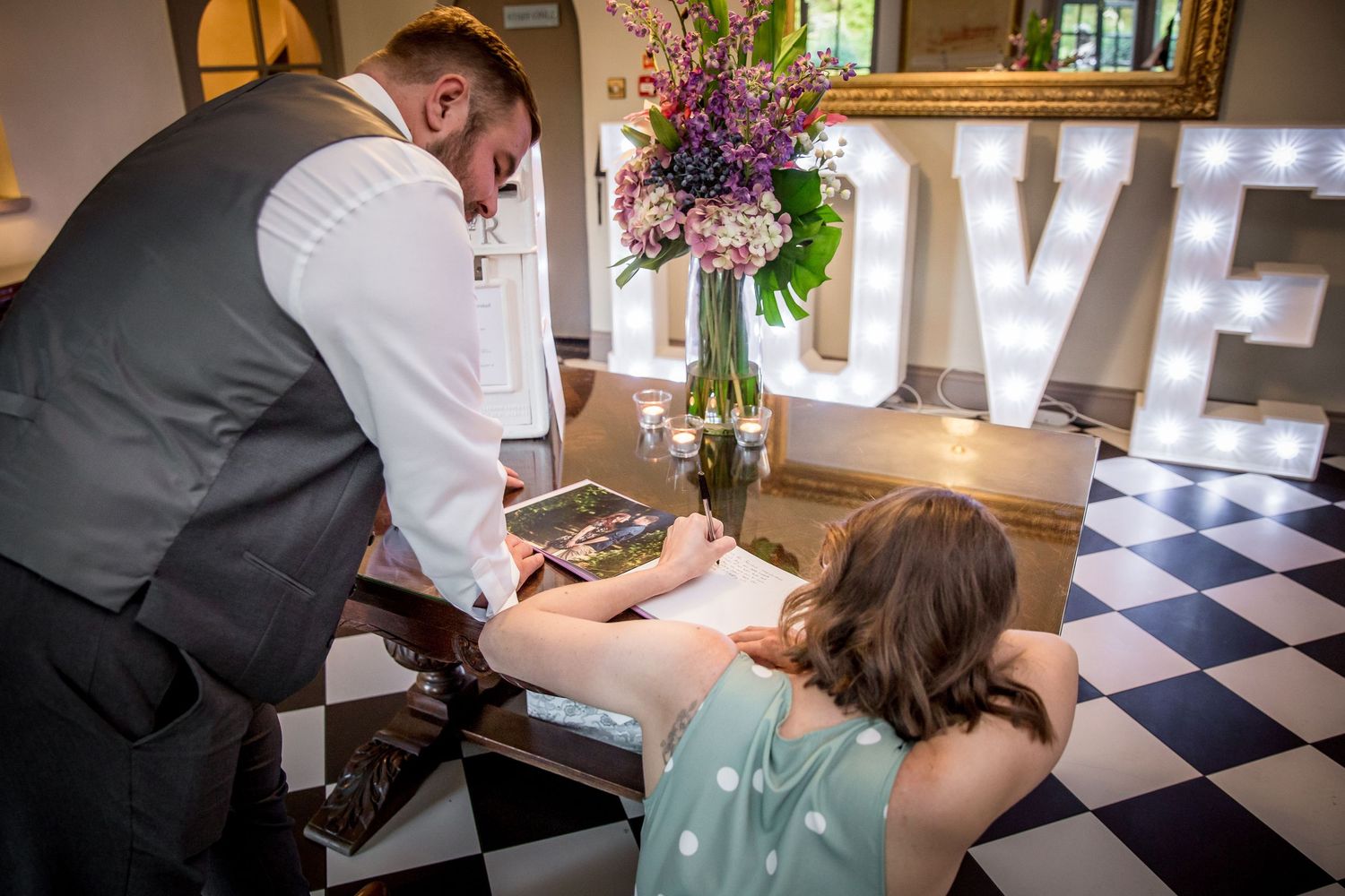 Guests at a wedding at Southdowns Manor sign a guest book in the main hallway of the venue