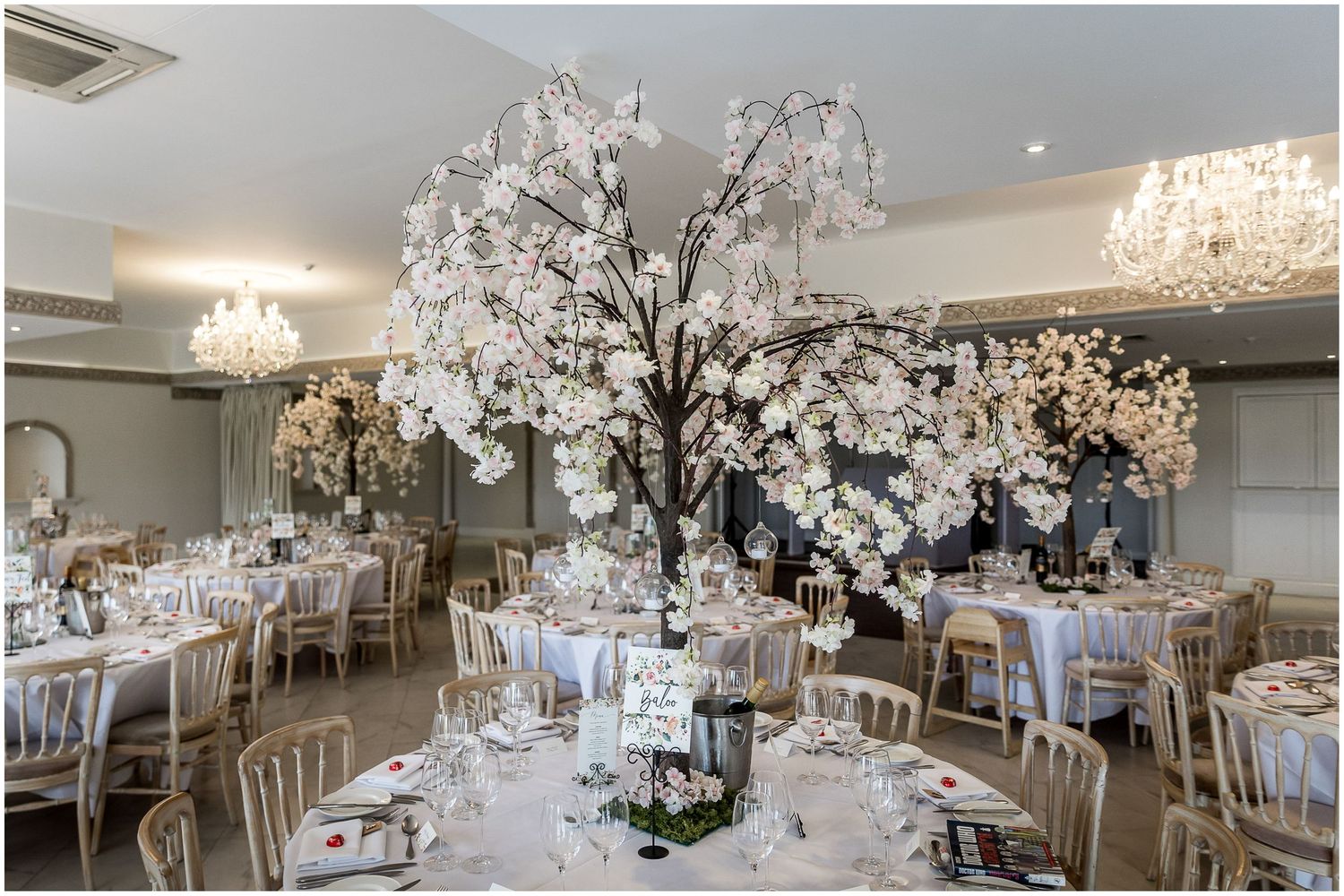 Luxurious wedding reception hall decorated with crystal chandeliers and white table settings.