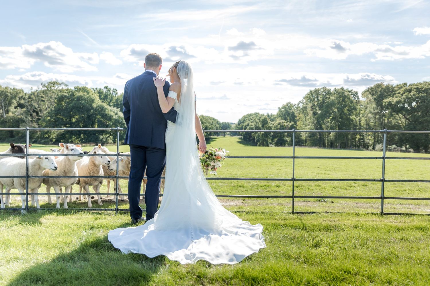 Wedding ceremony setup in a scenic countryside field with white chairs.