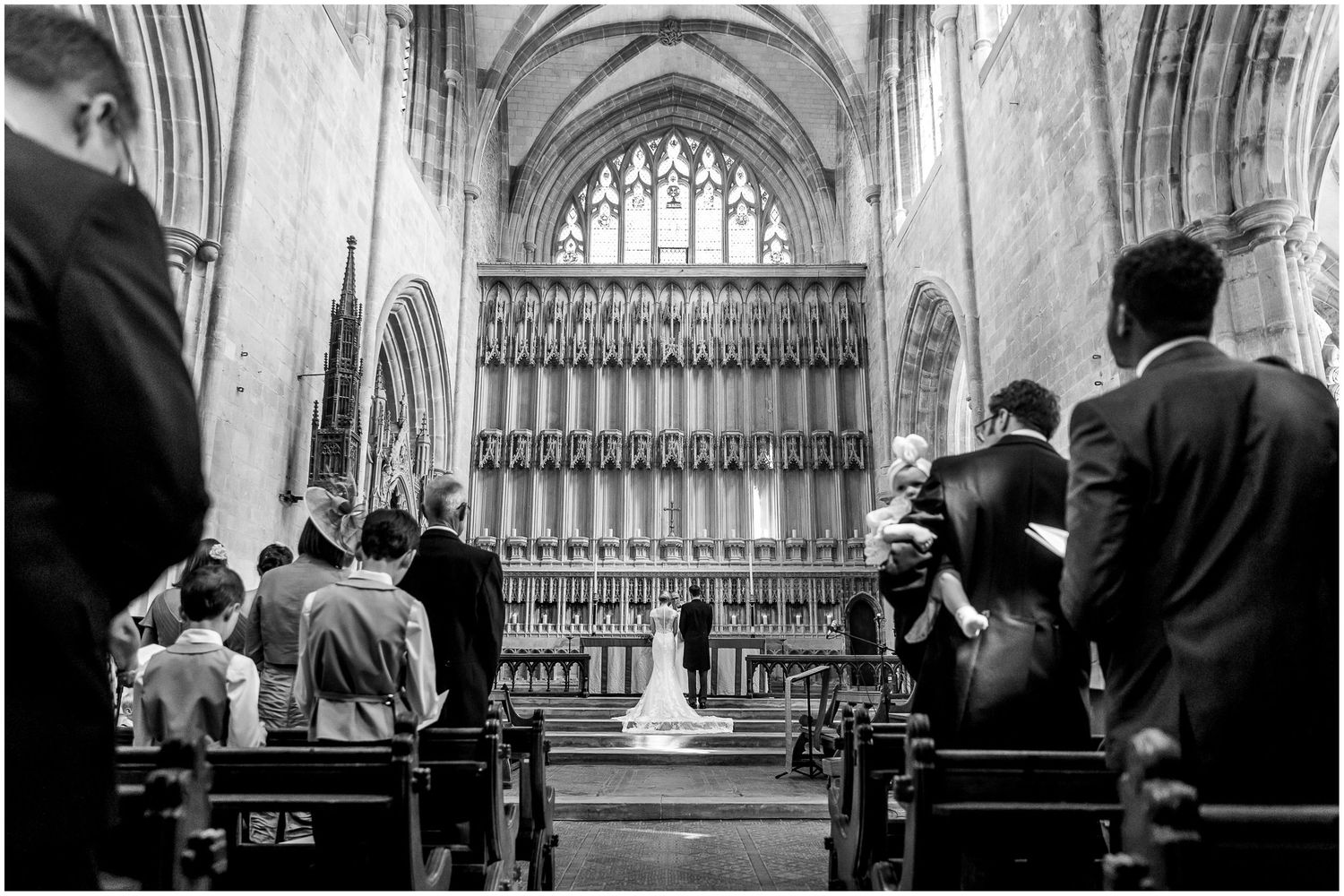 Gothic church interior with vaulted ceilings and arched windows during a wedding ceremony.