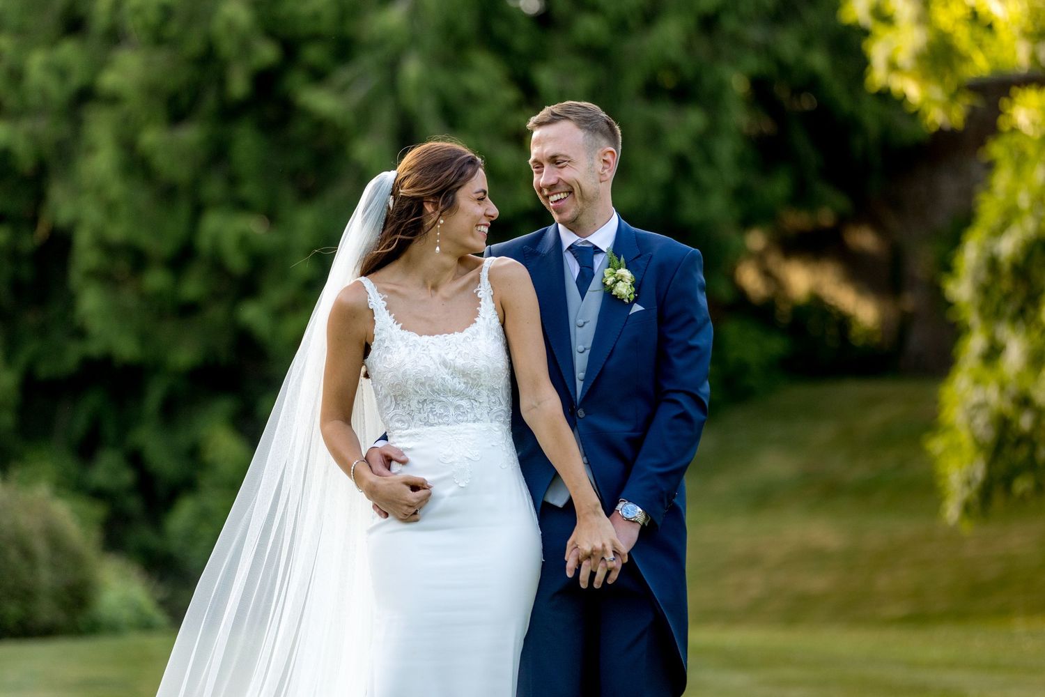 Newlyweds share joyful moment together in lush garden setting.