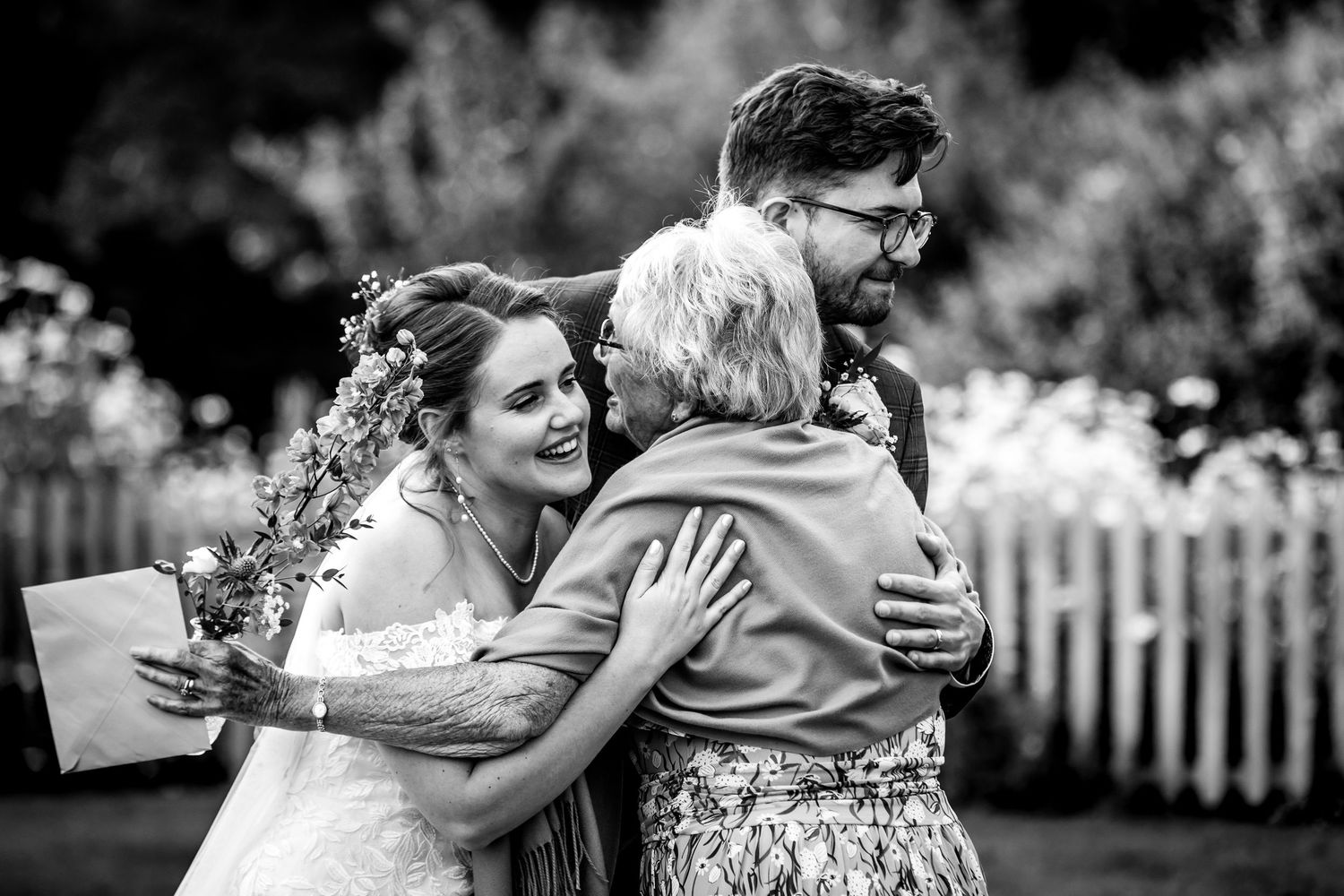 Black and white wedding photos showing emotional moments and embraces at an outdoor celebration.