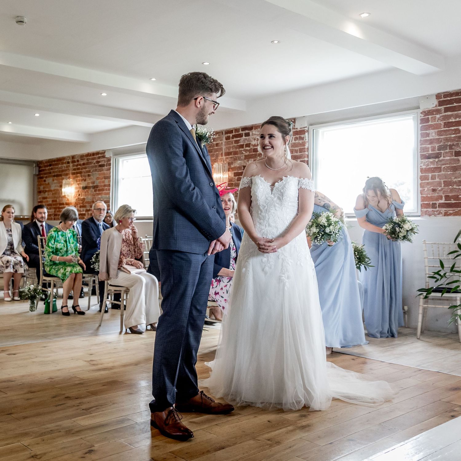 Wedding ceremony setup in a bright indoor space with brick walls and wooden flooring.
