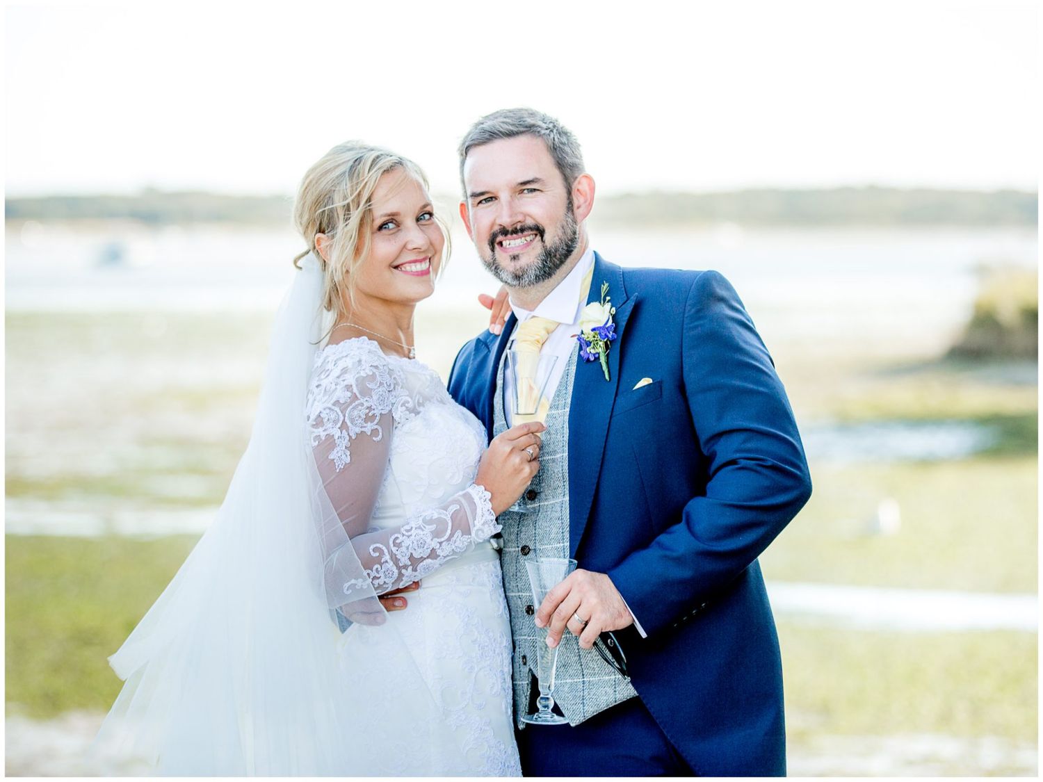 A couple in wedding attire shares a tender moment outdoors in a scenic natural setting during their special day.