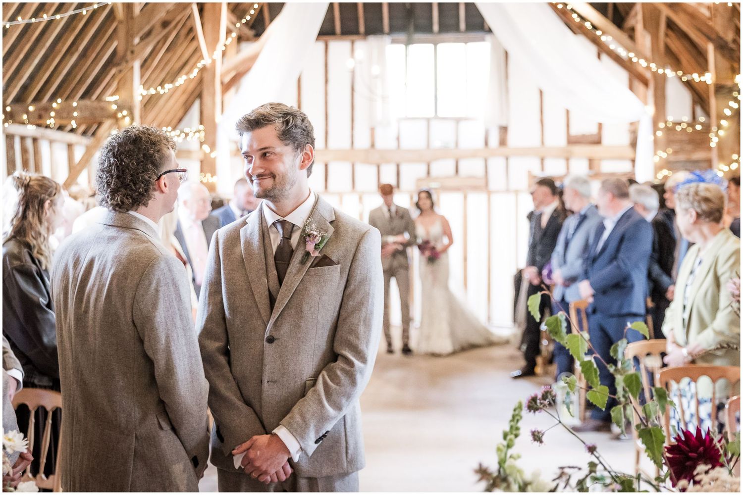 Wedding photograph of he groom standing at the end of the aisle at Clock Barn in Hampshire as the bride arrives