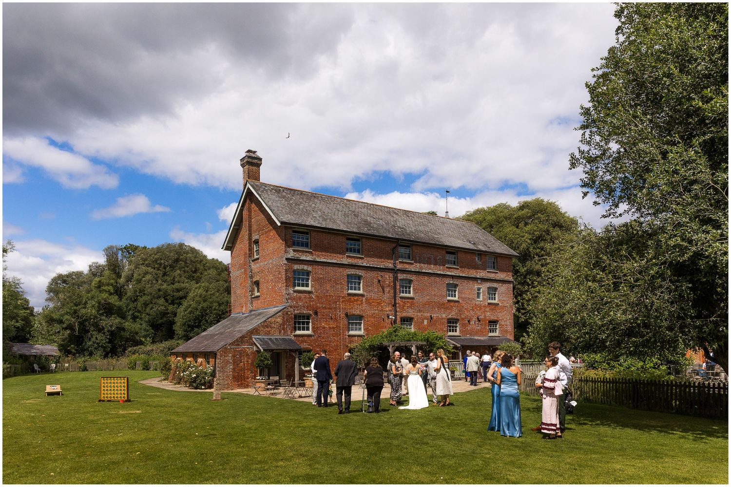 Wedding guests during the drinks reception in the gardens at Sopley Mill, Hampshire wedding venue