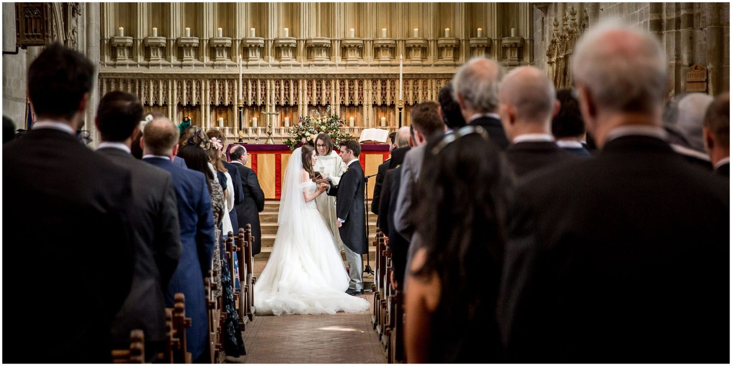 Elegant church wedding ceremony with guests seated in wooden pews beneath vaulted gothic arches.