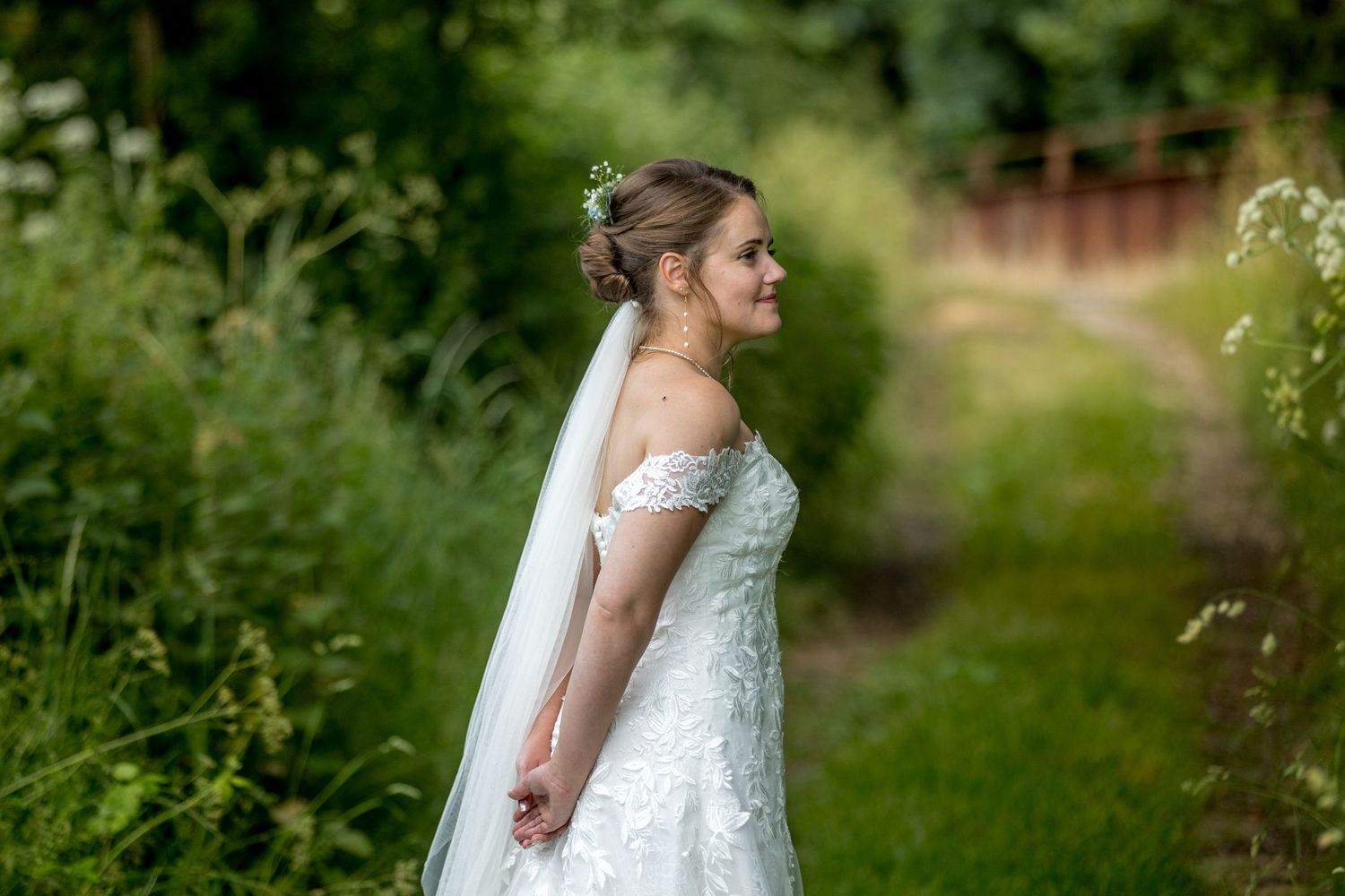 Wedding couple embraces in a lush garden setting with natural greenery and soft lighting.