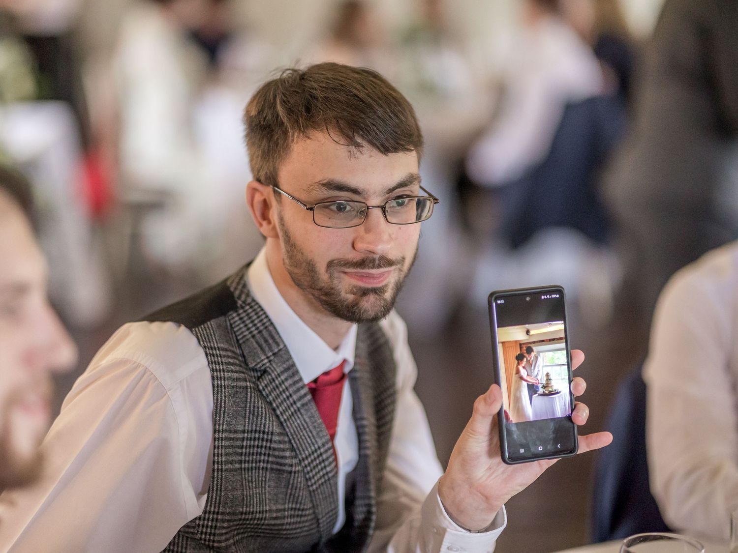 Wedding guests holding up phones to capture moments during a reception celebration.