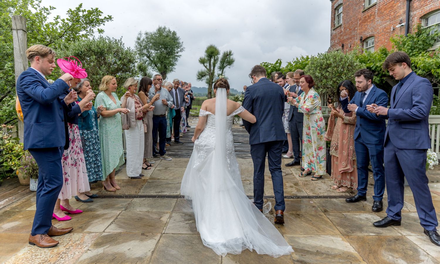 Outdoor wedding ceremony procession on stone path with guests lined up.