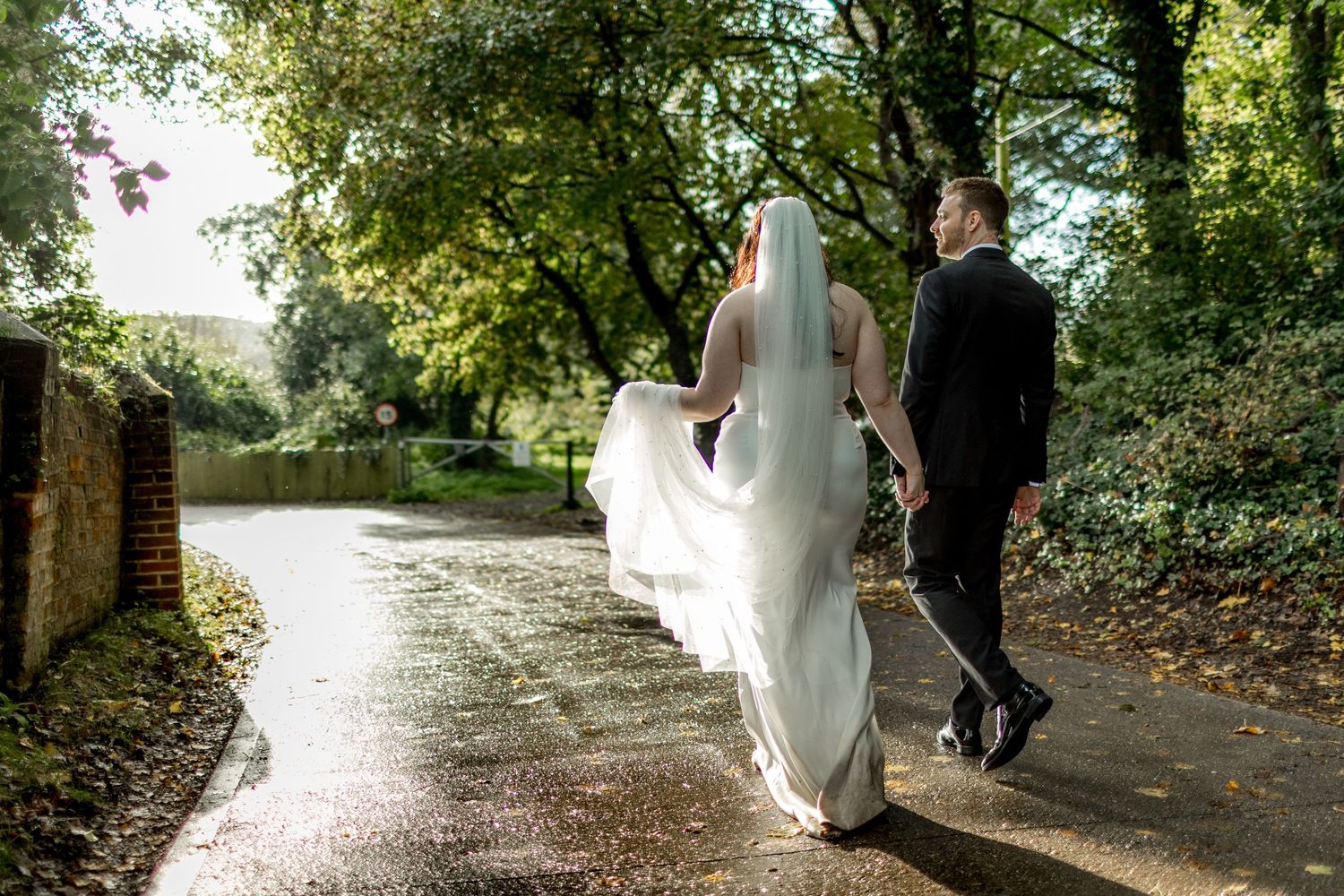 Wedding couple walking along a tree-lined path on their special day.