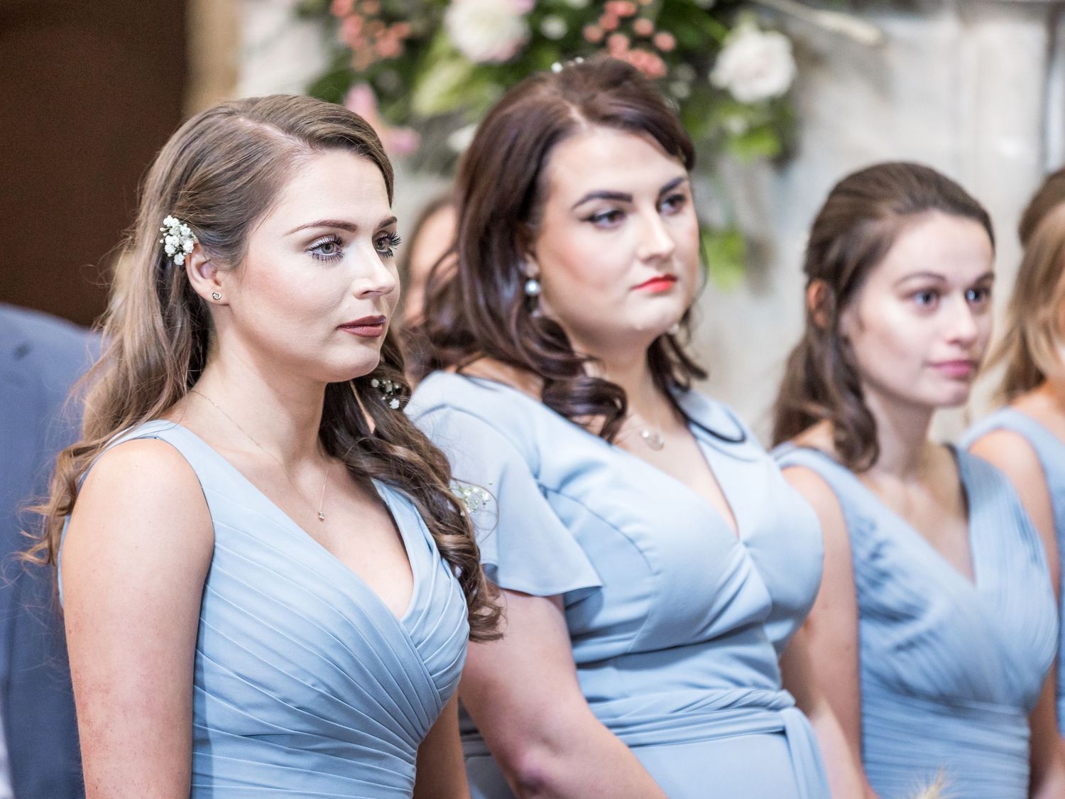 Bridesmaids in light blue dresses stand together during a wedding ceremony.