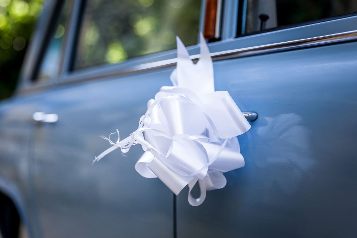 White ribbon decorations adorn a classic wedding car.