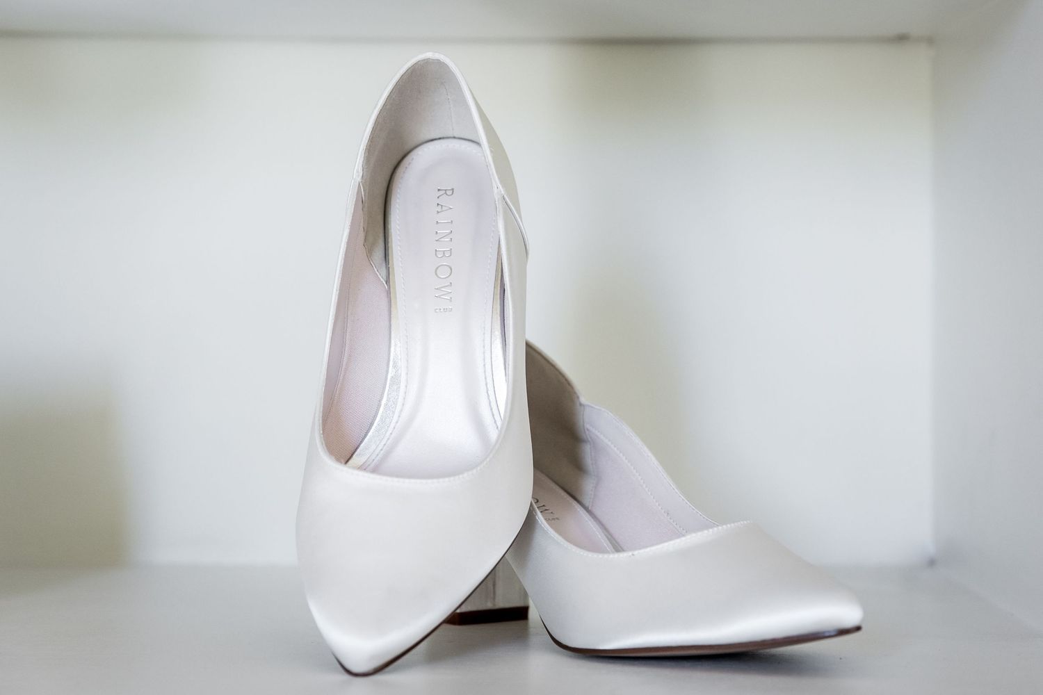 Close-up view of elegant white bridal shoes arranged in a row against a light background.