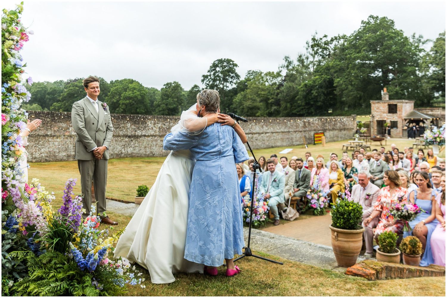 The bride hugs her grandmother during the outdoor wedding ceremony in the walled garden of the Holywell Estate