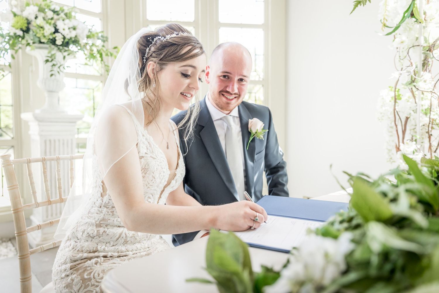 Wedding signing ceremony with white floral arrangements in an elegant indoor setting.