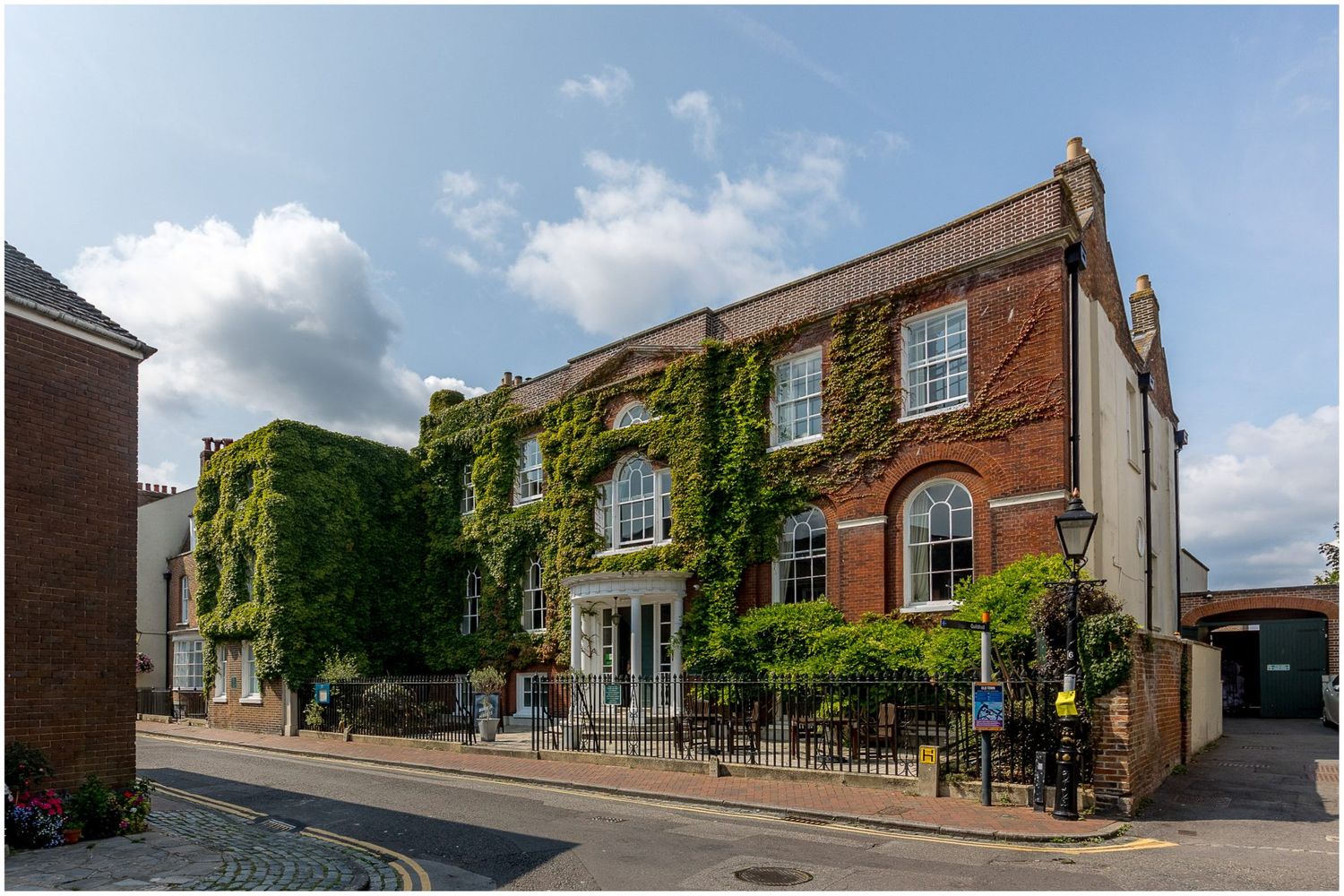 Beautiful red brick Georgian building with ivy-covered walls and classic windows.
