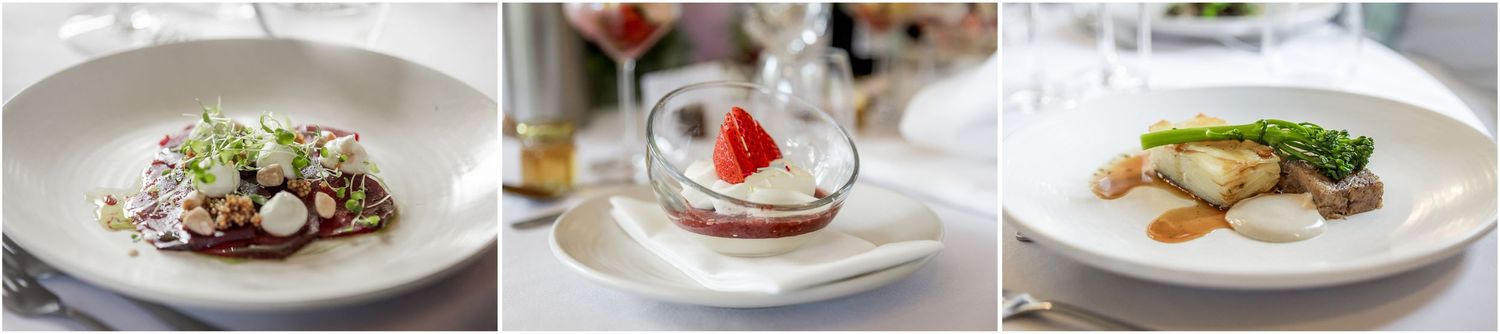 Beautifully plated gourmet dishes and wedding cake displayed at an elegant reception.