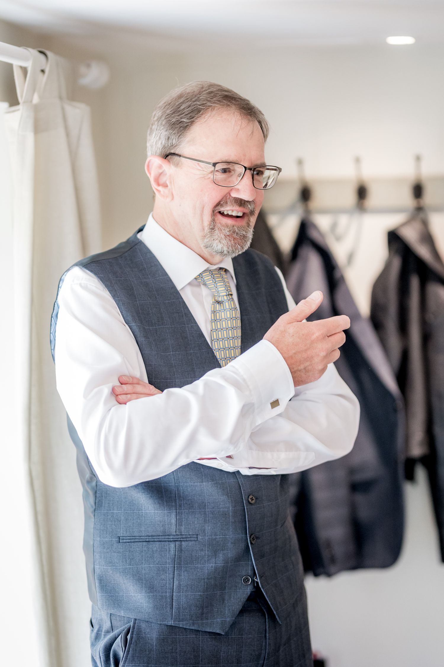 Person in grey vest and white shirt adjusts tie while getting ready.