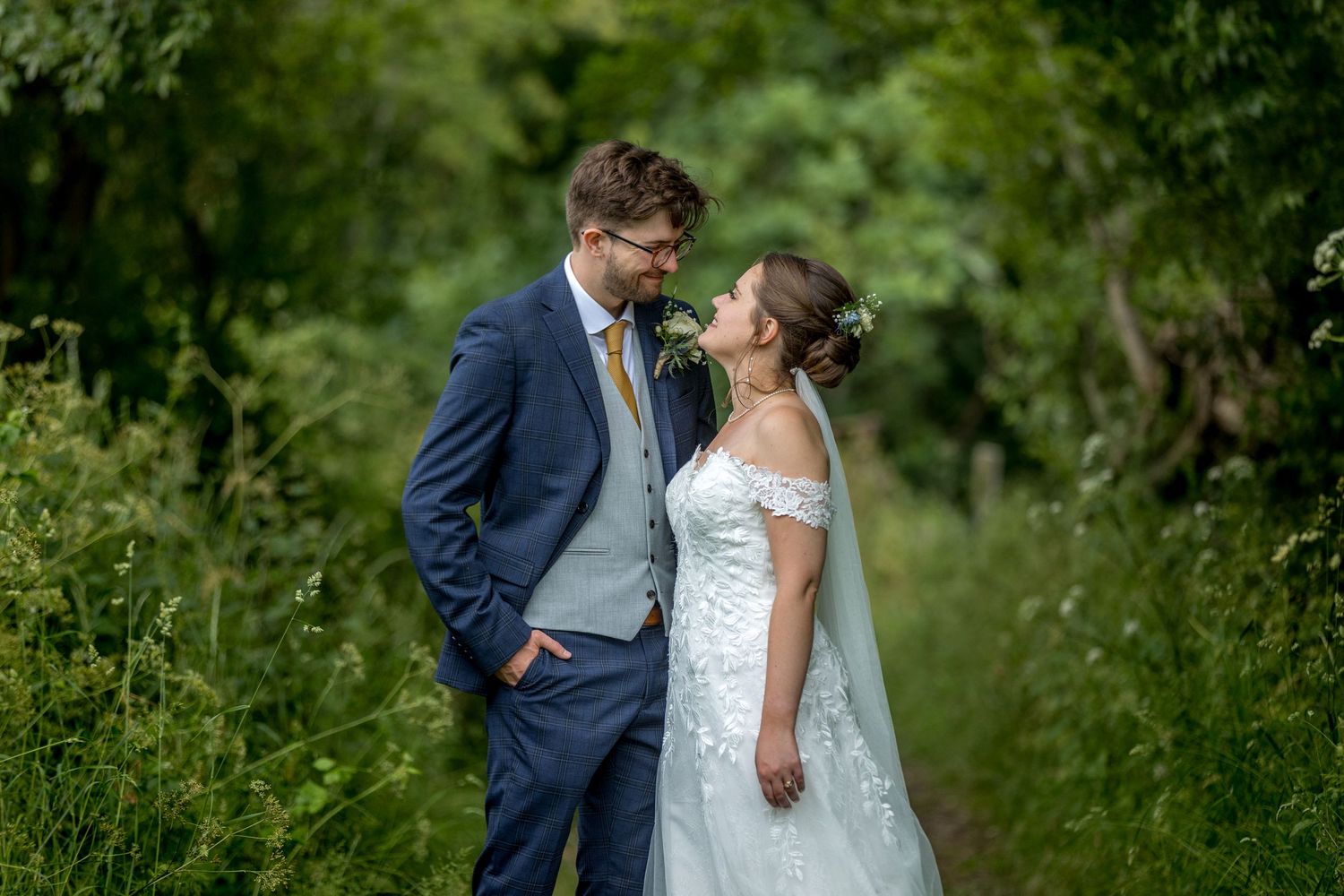 Elegant wedding couple photographed in a secluded garden setting.