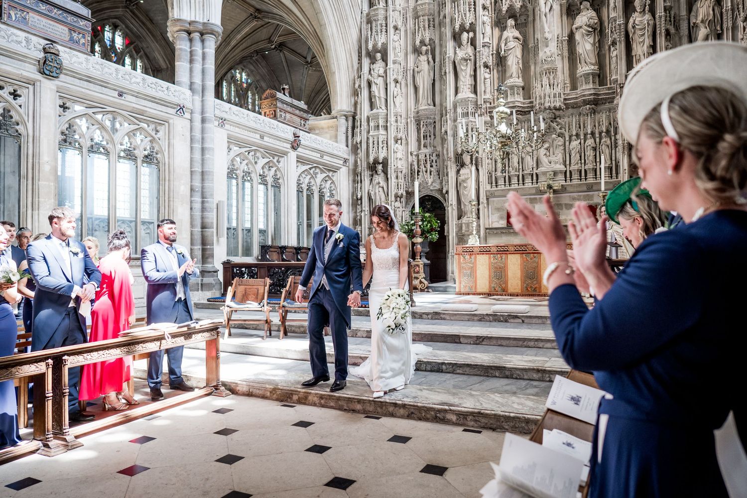 Panoramic view of a cathedral wedding ceremony with guests seated in wooden pews.