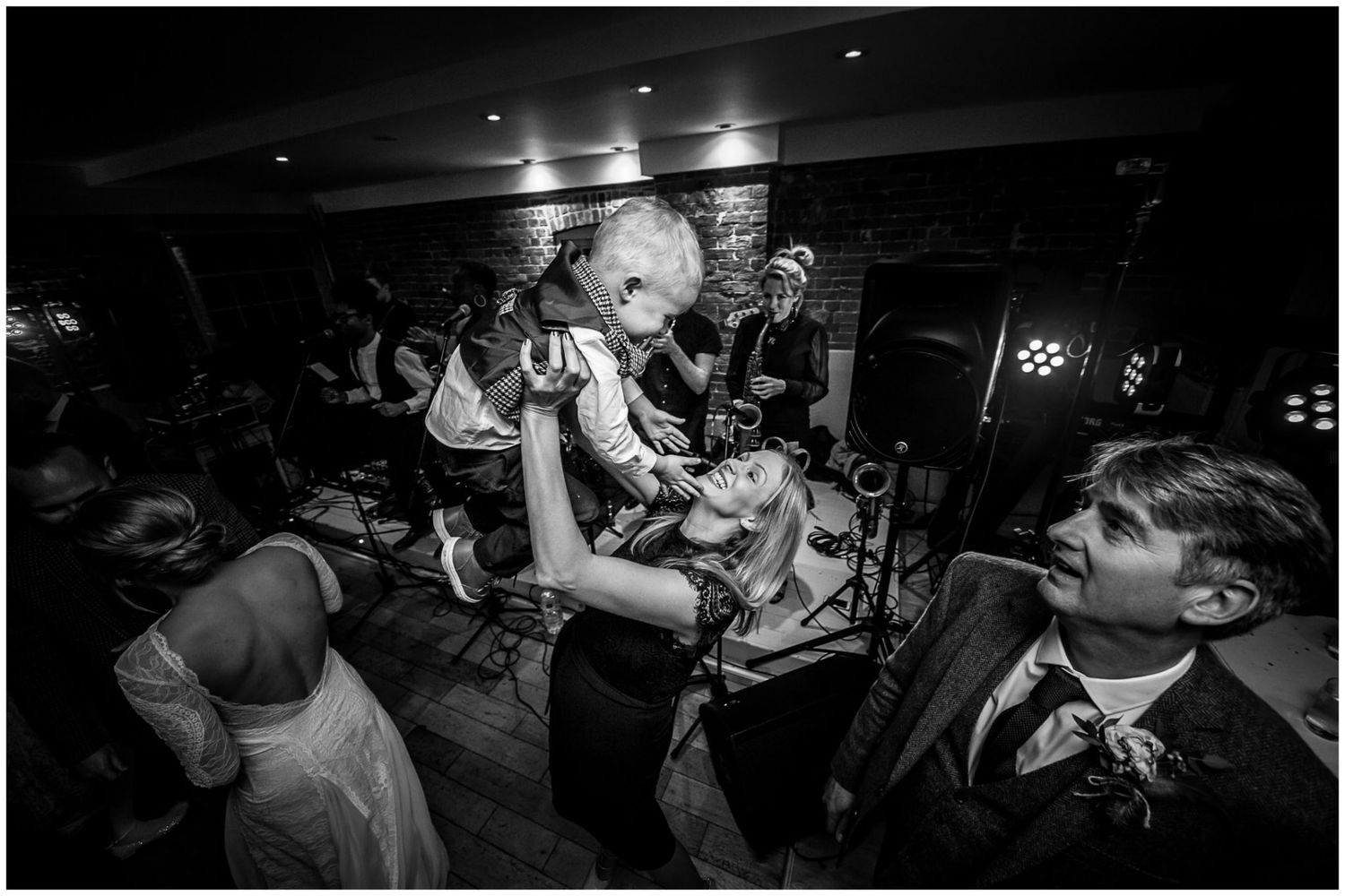 Low-light reception venue with guests dancing and celebrating on the dance floor.
