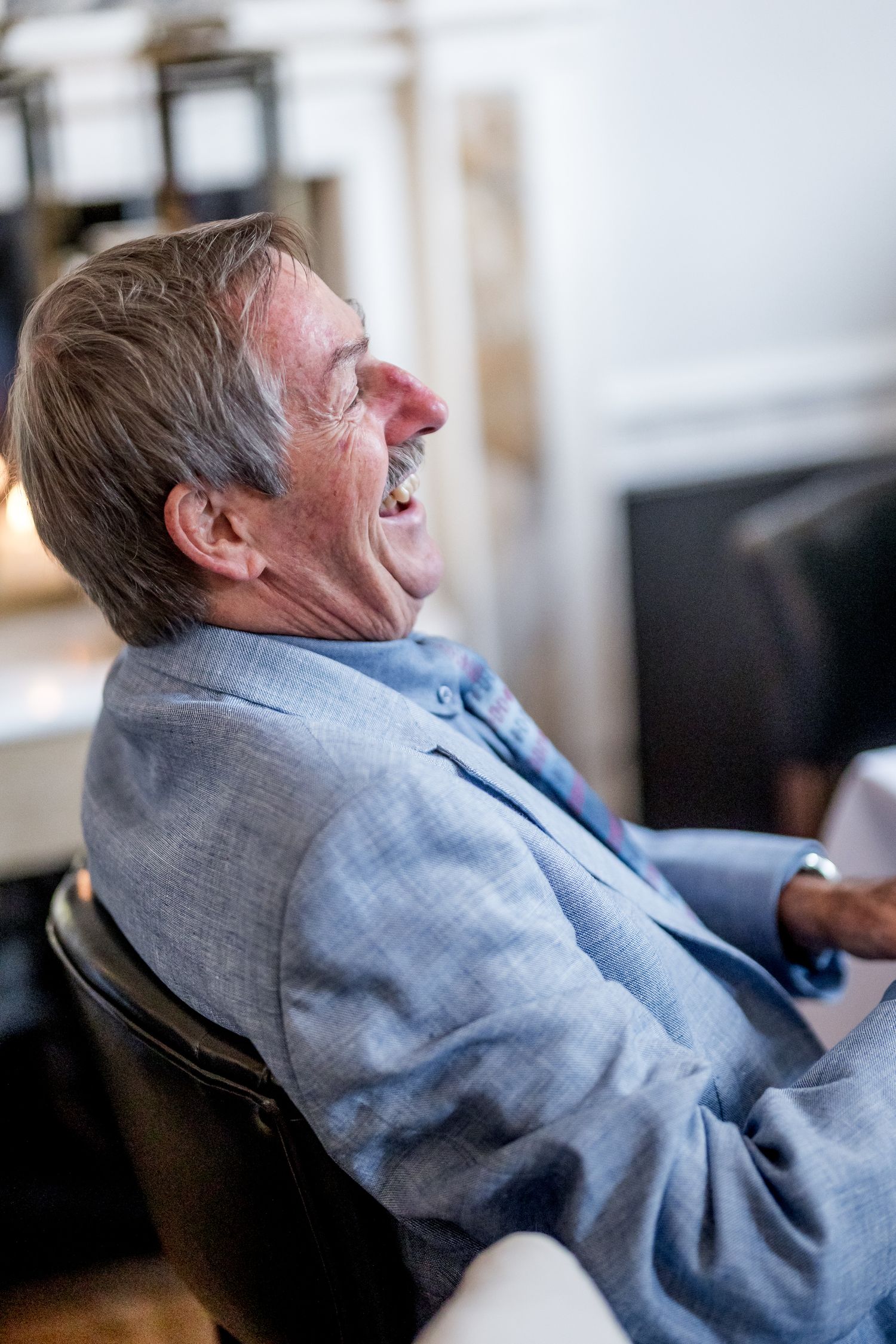 Person in grey suit jacket relaxing in comfortable chair during event.