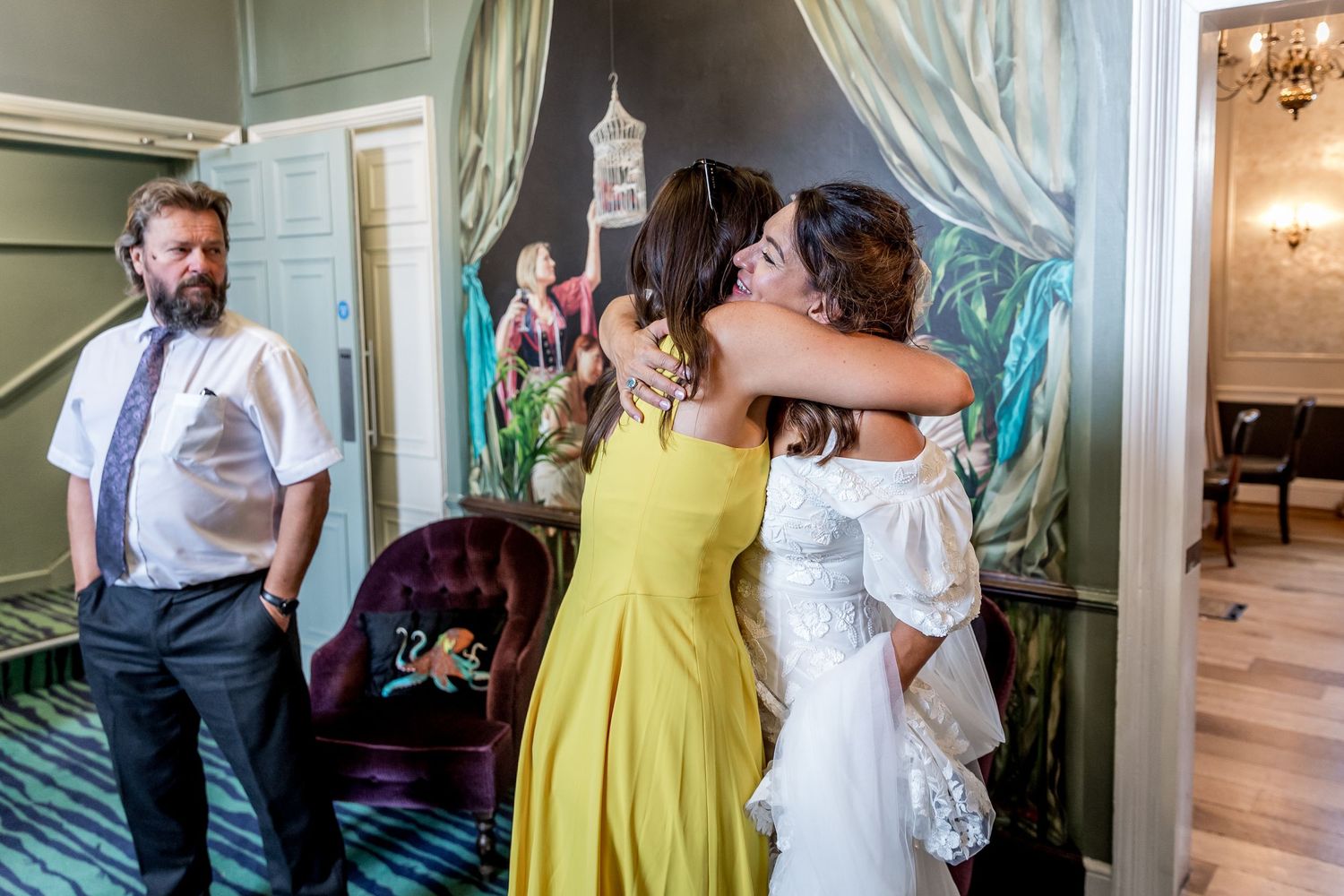 Celebration guests mingle in formal venue with yellow dress and white decor.