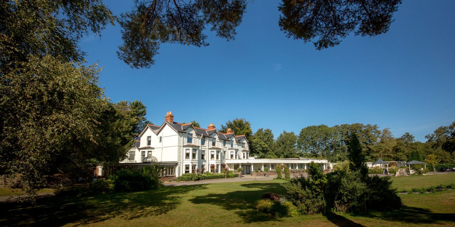 Aerial view of white Victorian mansion wedding venue surrounded by lush gardens.