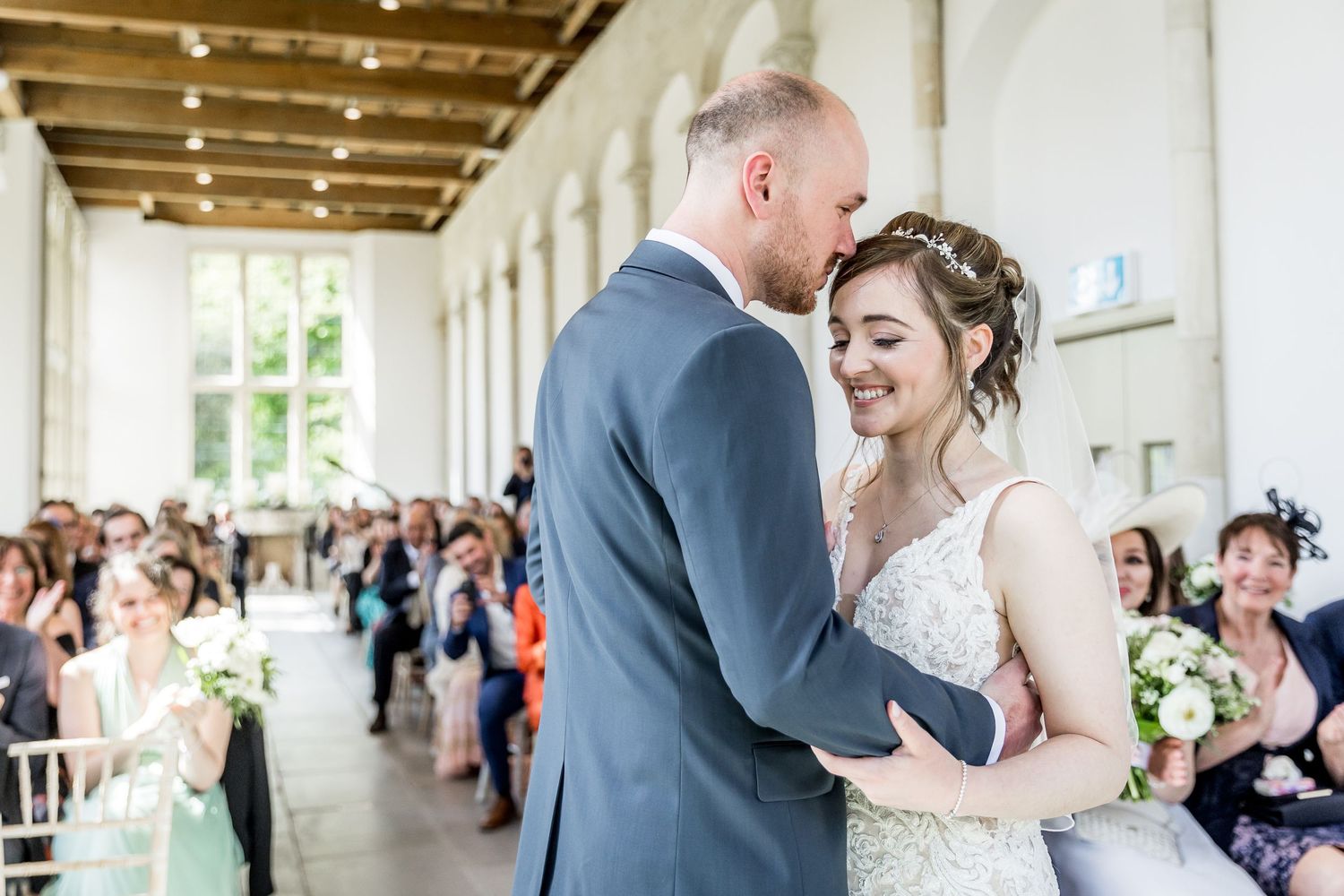 Elegant wedding ceremony moments captured in a bright columned venue with natural light.