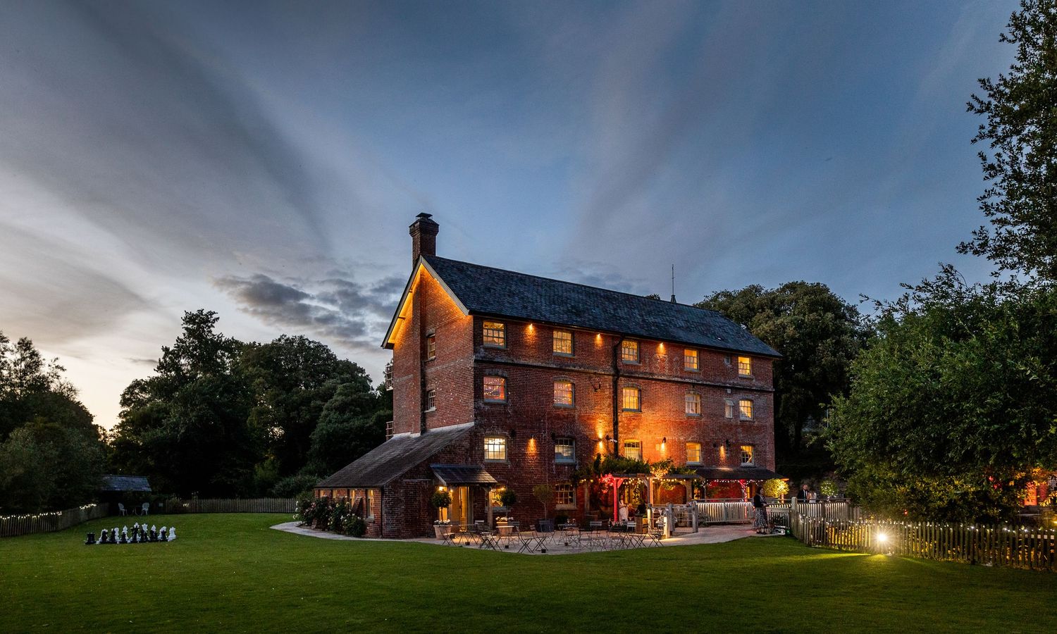 Evening panorama of illuminated country venue buildings with dramatic sky.