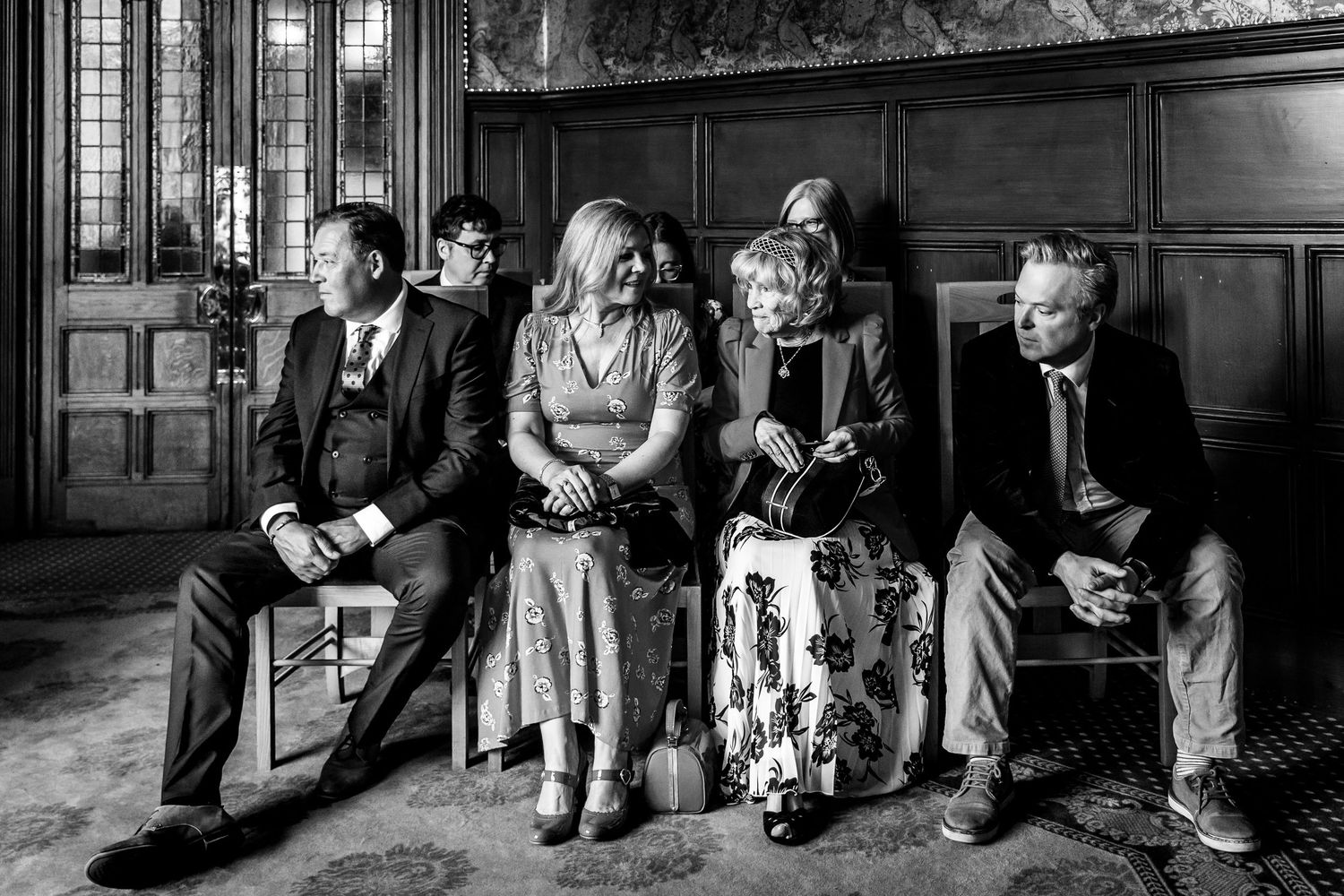 Wedding party seated in a wood-paneled room with vintage decor.