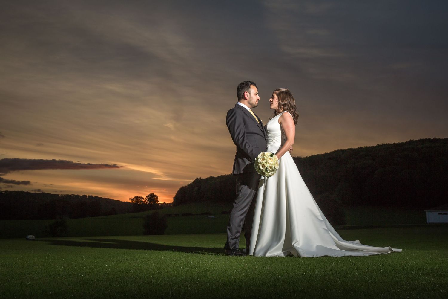 Dramatic sunset wedding photography silhouettes against an orange and purple sky.