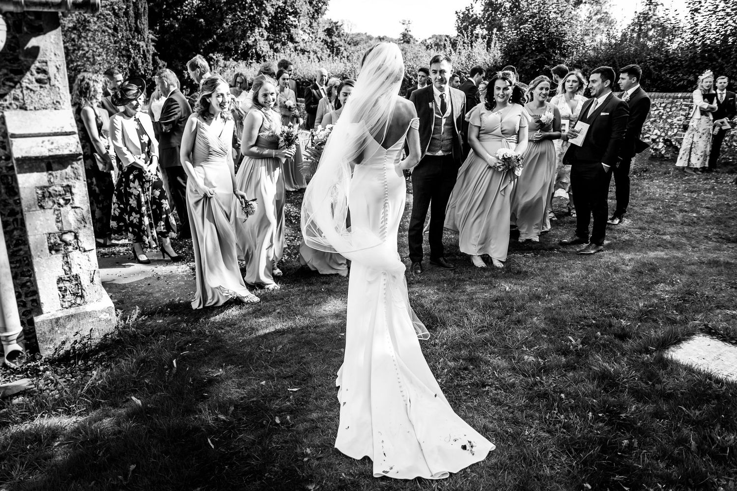 Black and white photo of wedding guests forming a receiving line outdoors.