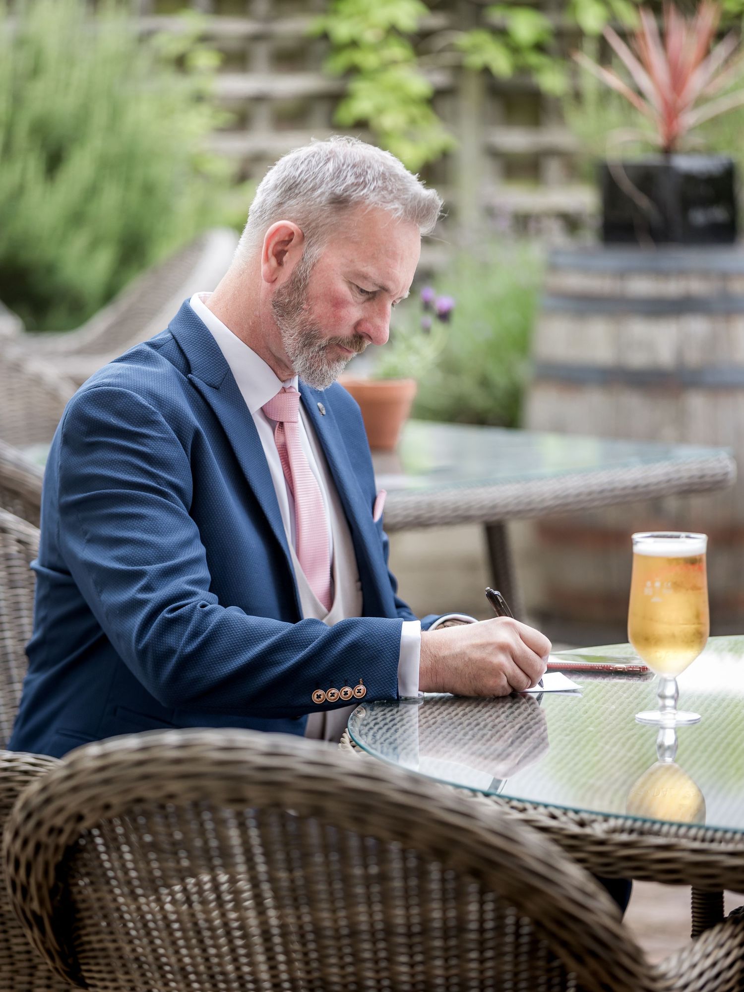 Person in navy suit enjoying a drink at outdoor patio furniture.