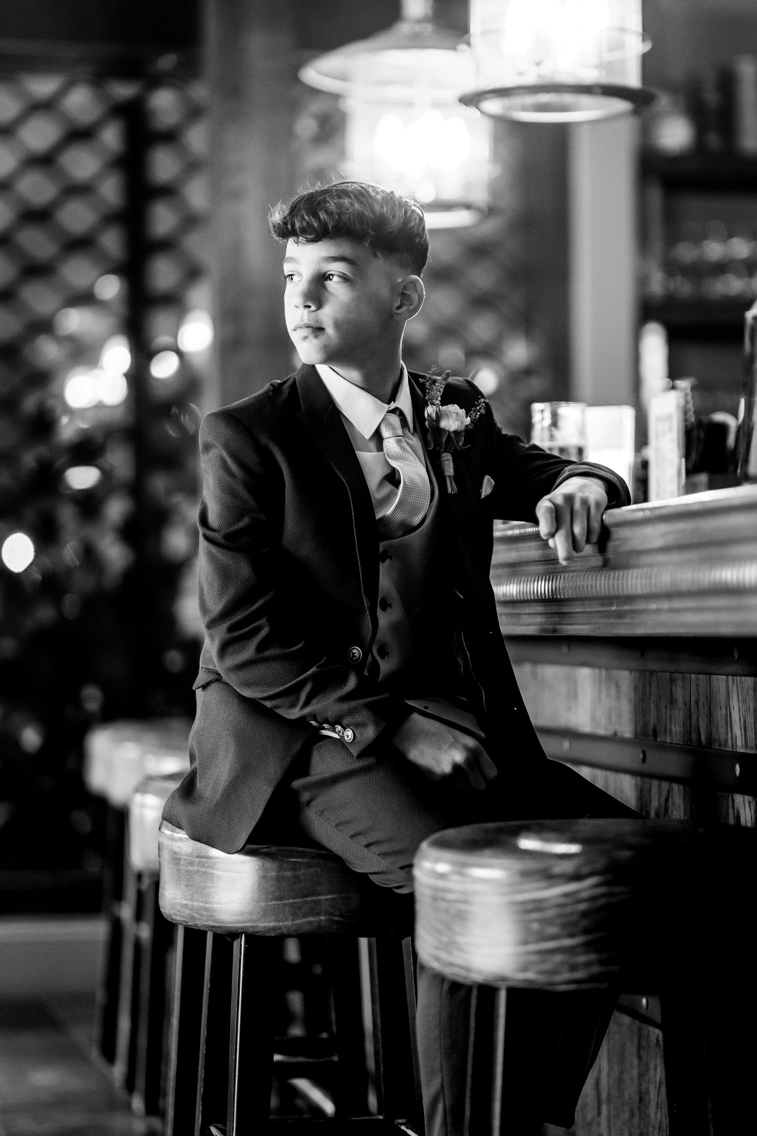 People sit at a dimly lit bar counter in black and white photography.