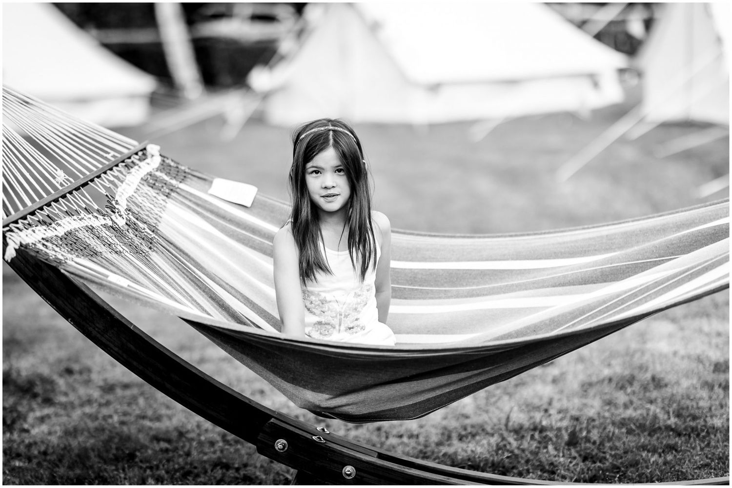 A hammock swings gently in an outdoor setting with natural sunlight filtering through.