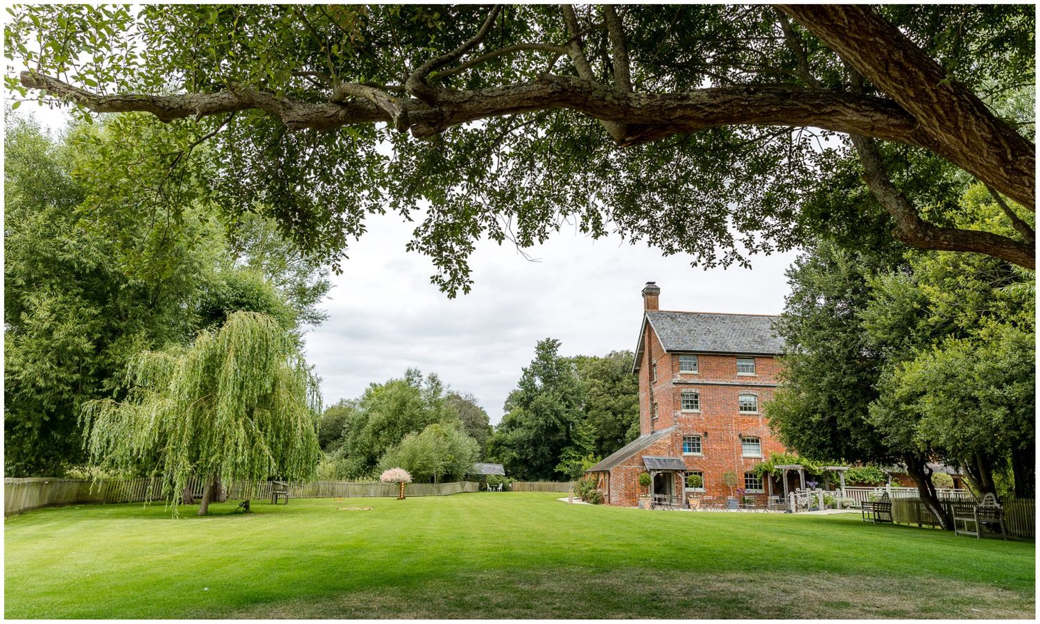 Panoramic view of a rustic countryside estate with lush green grounds and trees.