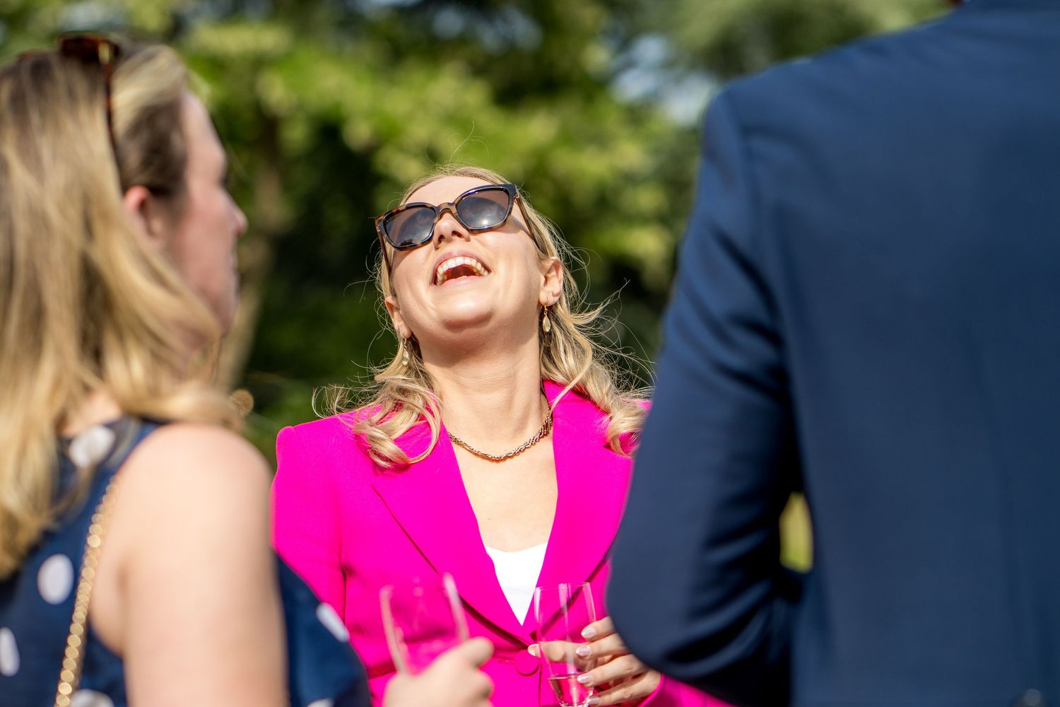 Guests sharing laughter during an outdoor summer wedding reception.