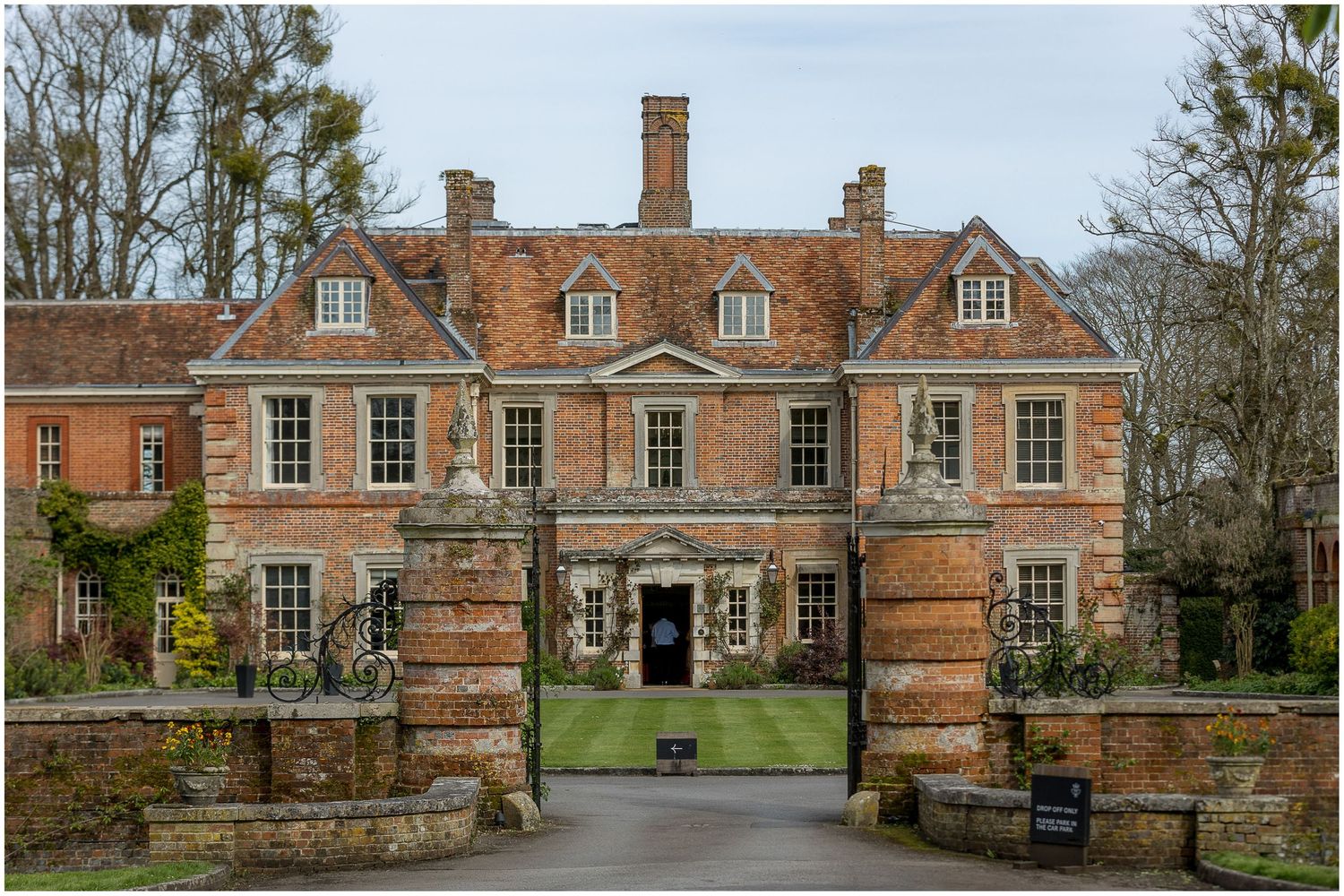 Panoramic view of a historic red brick manor house with symmetrical architecture.