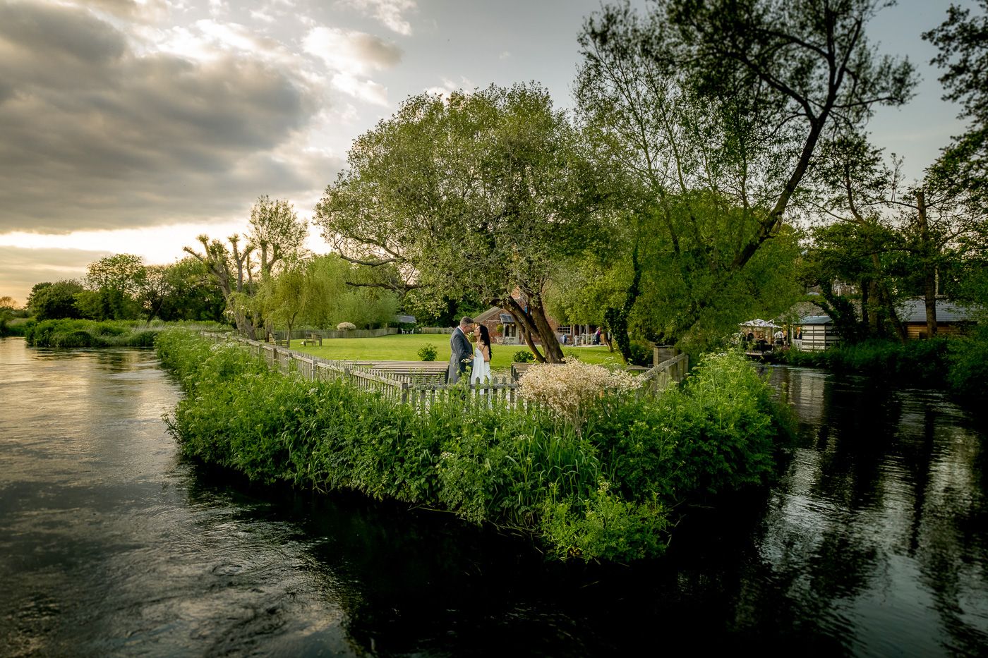Scenic riverside landscape with lush green trees and reflective water during golden hour sunset.